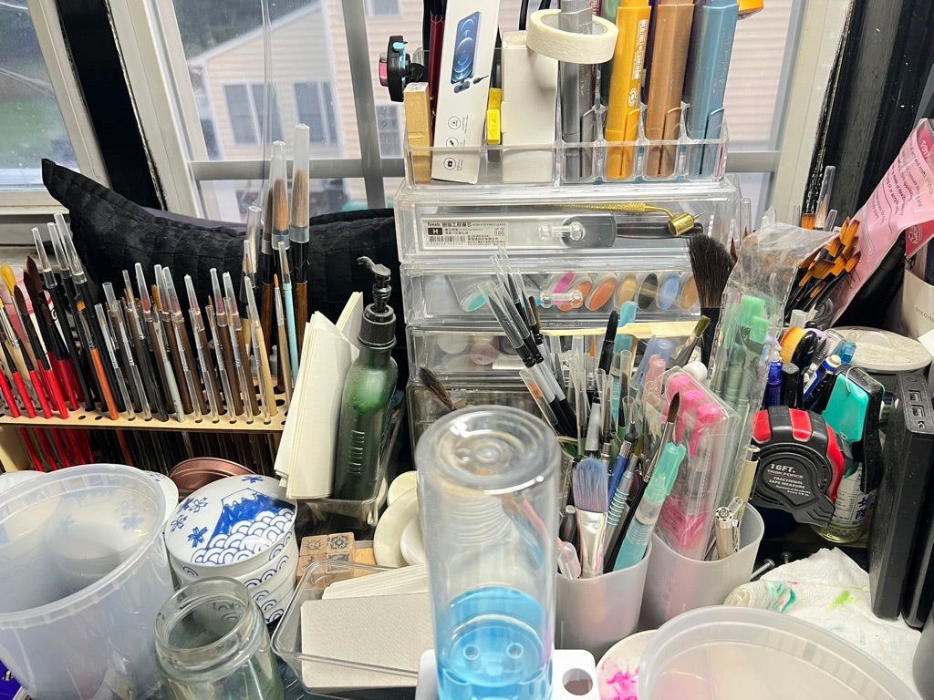 a collection of paintbrushes and paint tools on LHS's studio desk