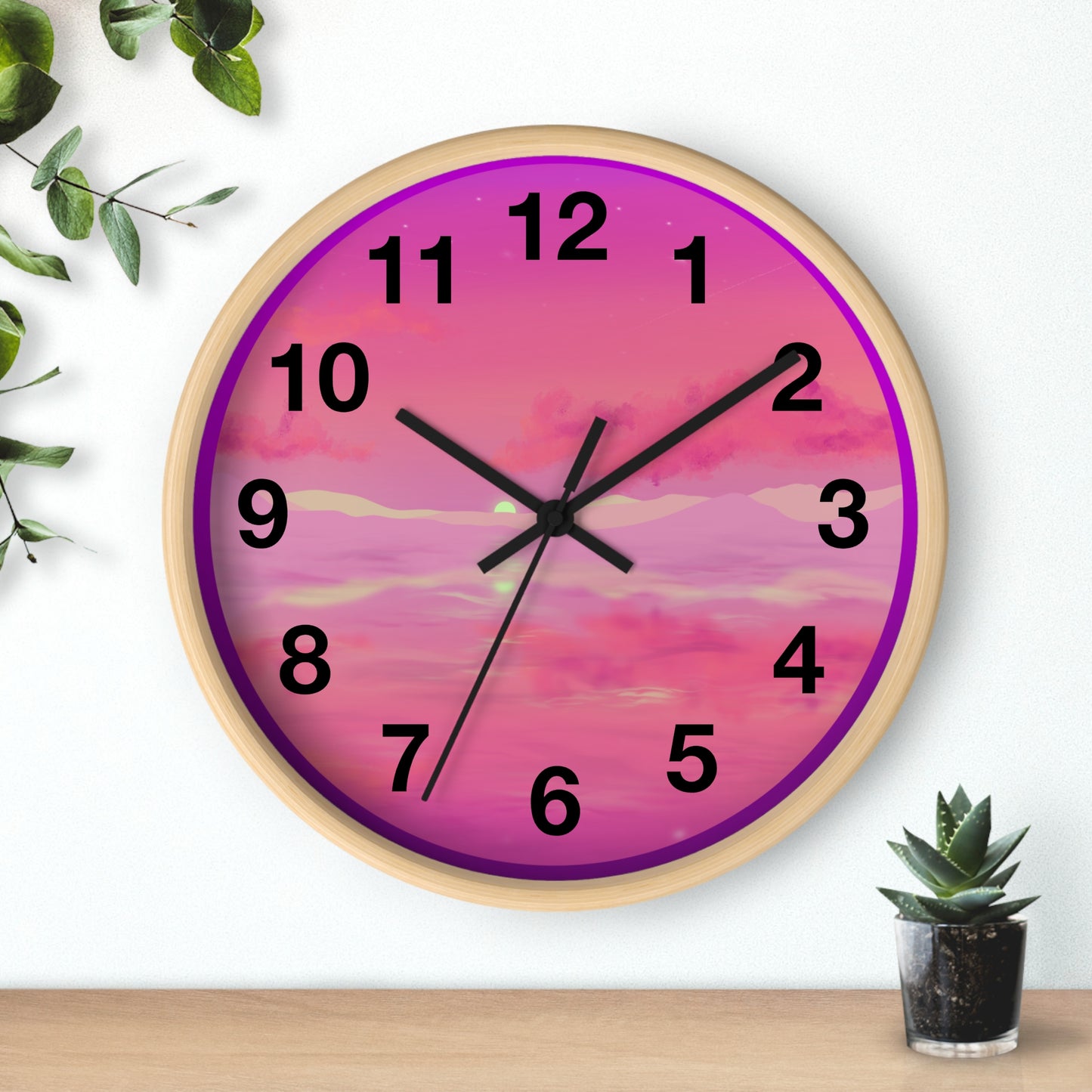 This is the 10" Wooden Base Pink Dreamscape Wall Clock with black hands by Lee Hansheng Studios.The front of the image with two black clock hands, numerals and the illustration behind it.The illustration has the sky and clouds. Different pinks and hues blended into the clouds and spreads outwards.There are dark purples on the side and yellows near the middle of the art piece. It is on a white background with leaves to the left, succulent plan on the right with a wooden board.