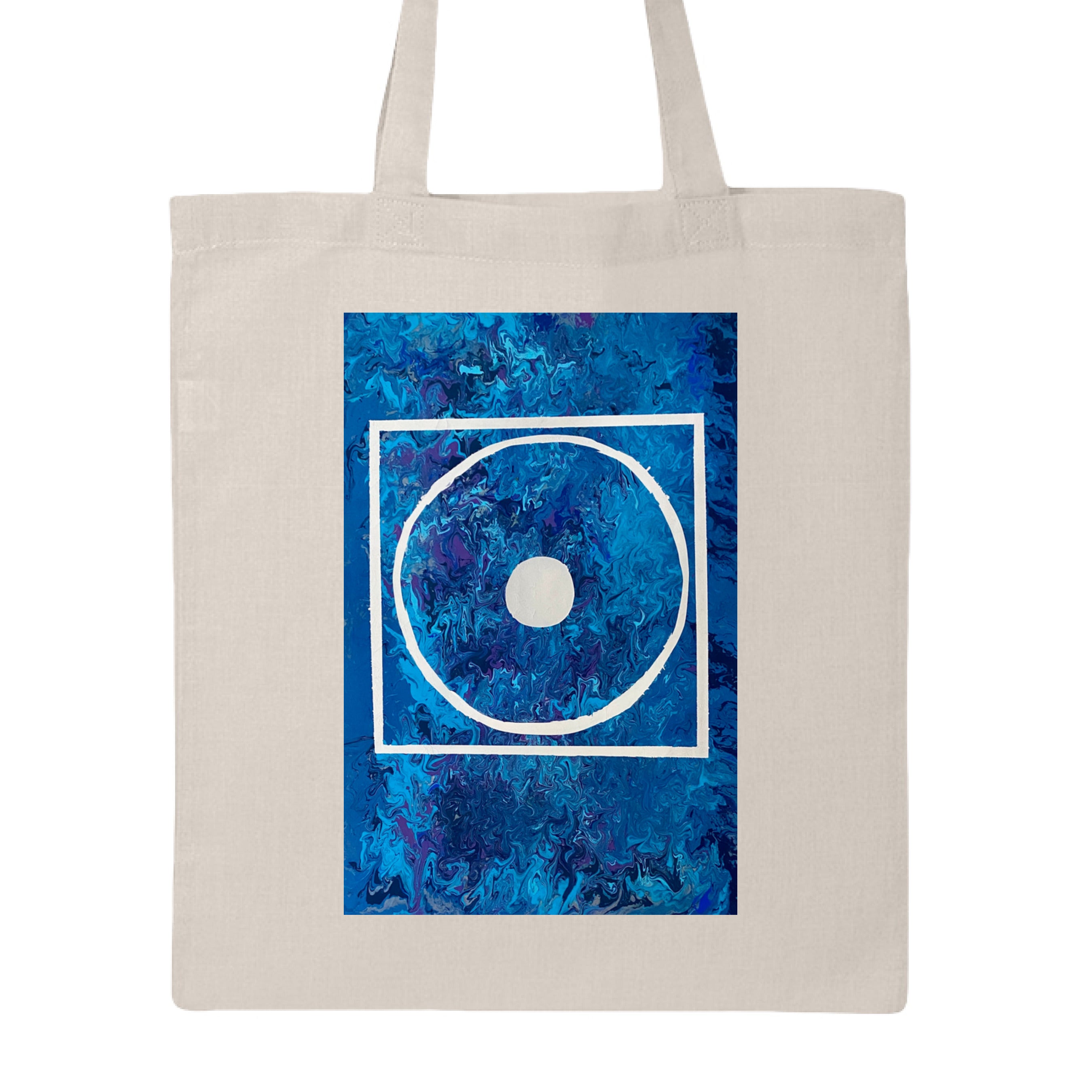 This is the Natural Big Low Canvas Tote by Storm Garden Studio. This is showcasing the front of the tote. The illustration is rectangular and has a white filled in dot, within a outlined circle, within a outlined rectangle. The background is a mix and dip of different blues. The tote is against a white background.