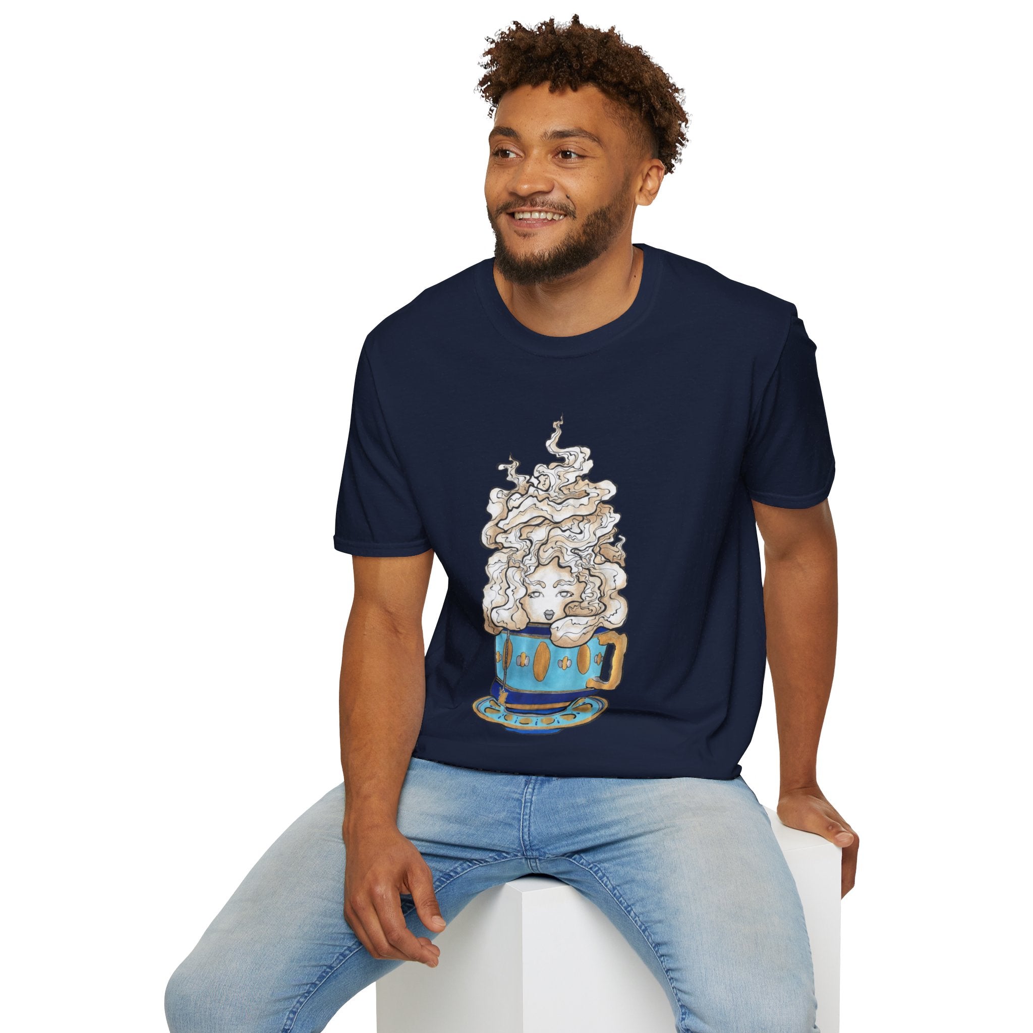 This is the Navy Earl Grey Softstyle T-Shirt by Chris Foster Design. It comes in sizes XS-5XL. The illustration is of a gold, light blue and dark blue teacup with a tan, yellow and white steam. The steam is swirly and goes up and outwards. In the middle is a lady's face. A smiling man sitting on a white podium with one hand on the back edge, light jeans, looking to the left and wearing the t-shirt.