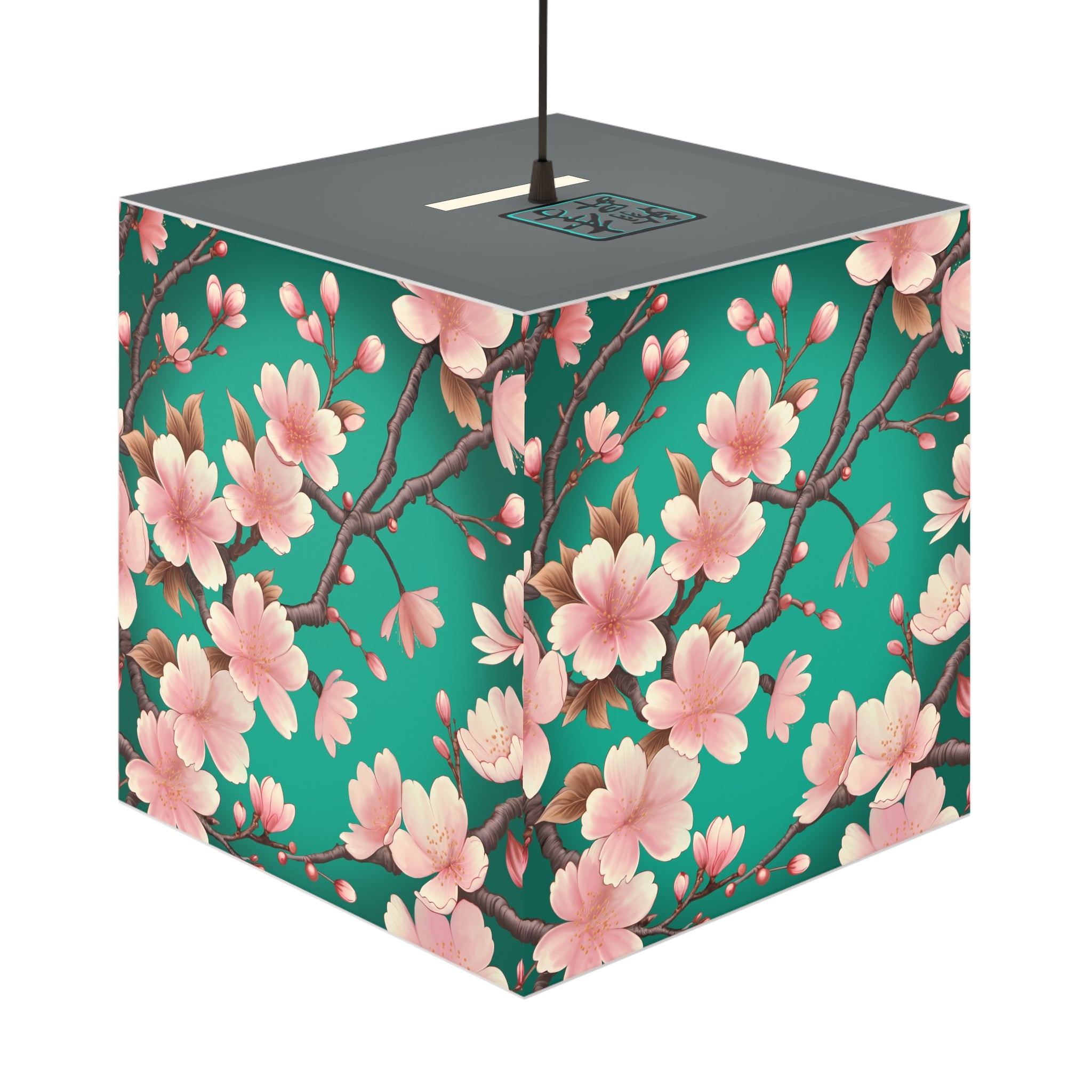 This is the Pendant Sakura Light Cube Lamp by Lee Hansheng Studios. The illustration is all around has a blue/teal background, 3-4 thin dark wood branches with pink/light pink buds on each stem. There are blooming and already flowered sakuras on each branch. There is about 3-4 inches between the end of the illustration and the sides of the lamp. The cord has a sleeker and plug-free option. The cube lamp is shown hung up. The gray top can be seen with the logo where the cord is being hung.
