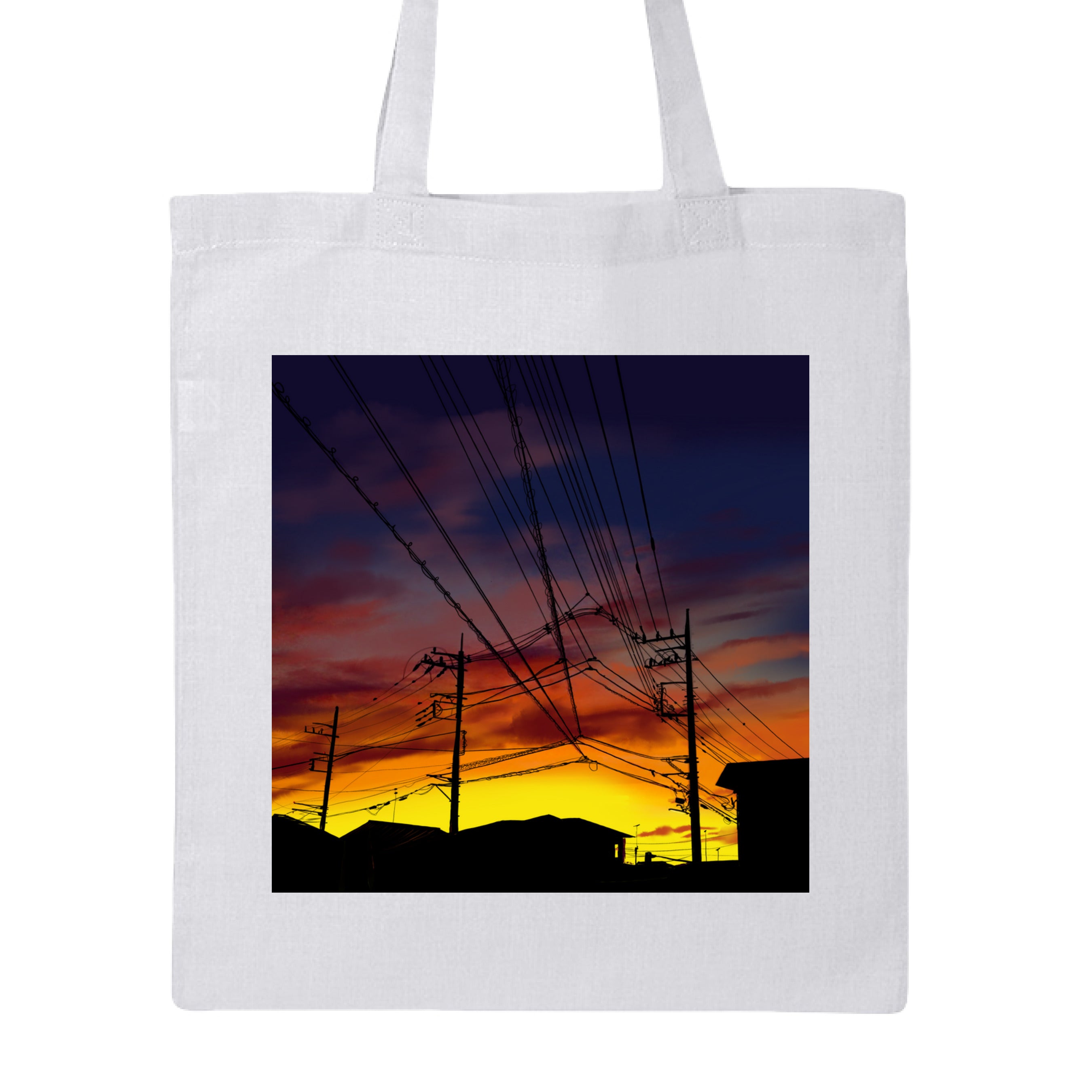 This is the White Saitama Sunset Canvas Tote by Lee Hansheng Studios. This showcases the front. The illustration shows the silhouettes of rooftops and power lines against a sky ablaze with golden yellows, deep oranges, and purples. The buildings are in the background on the bottom. The clouds are a mix of pink and reds. It is against a white background.