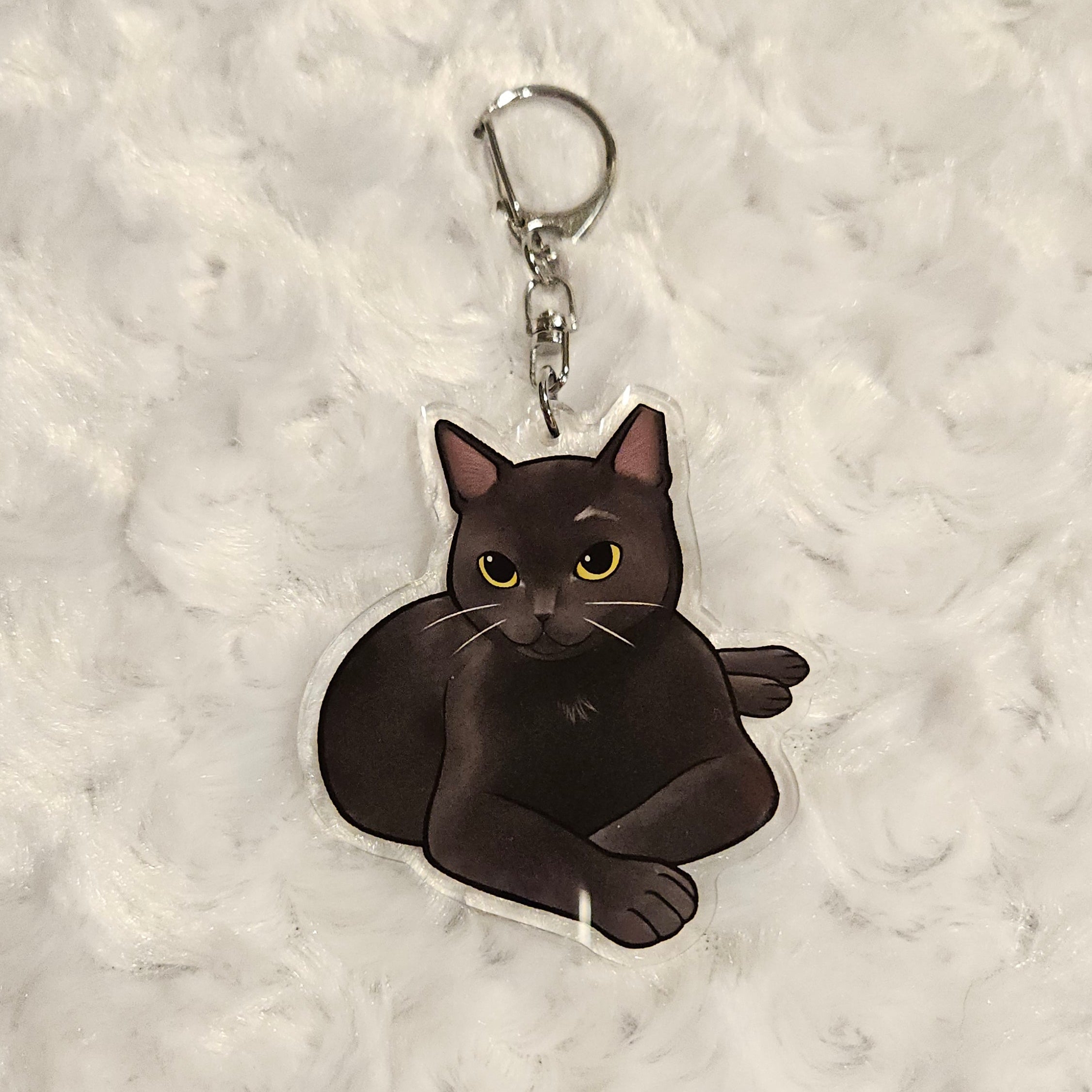 Black cat-shaped keychain on a textured gray background