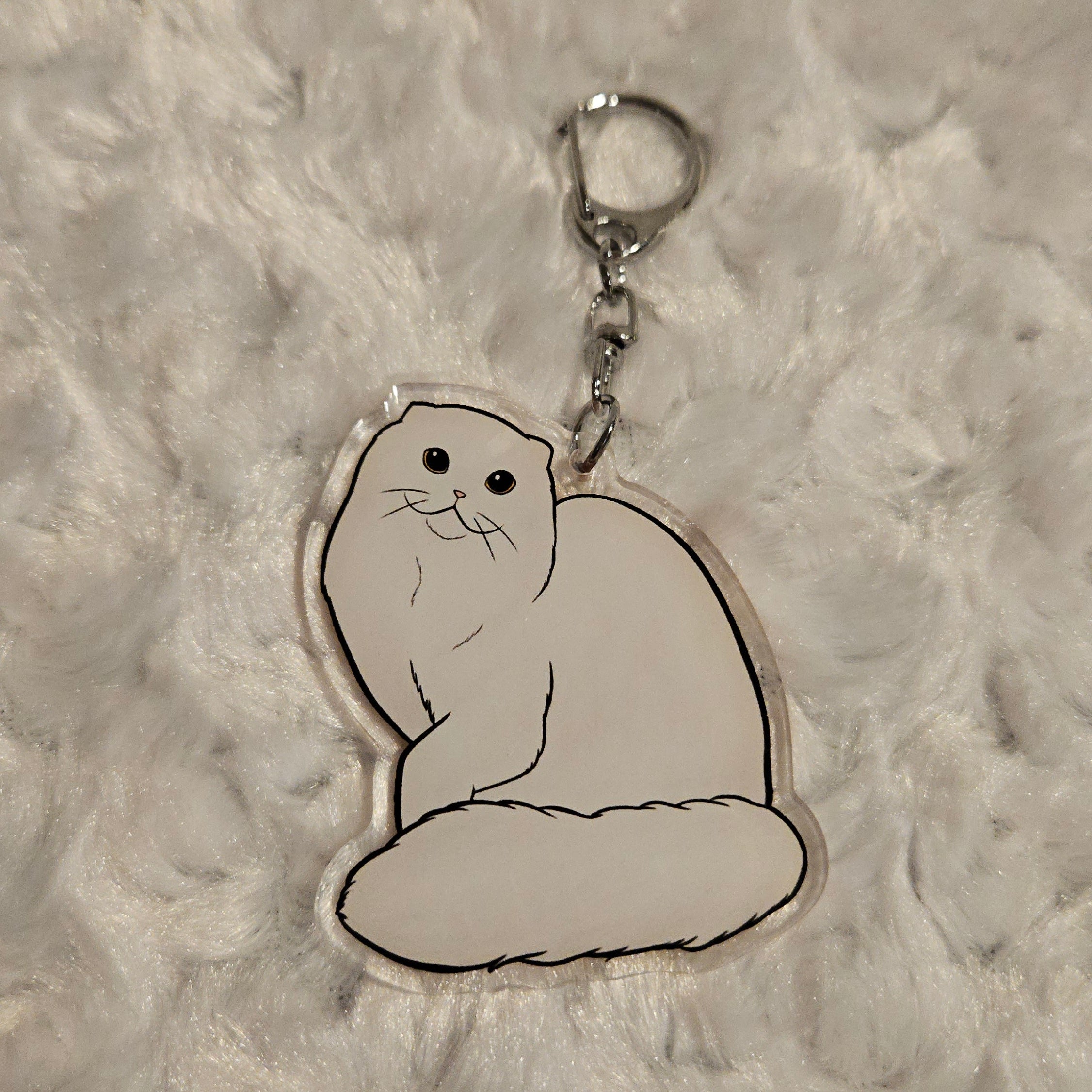 Keychain with a white cat design on a textured gray surface