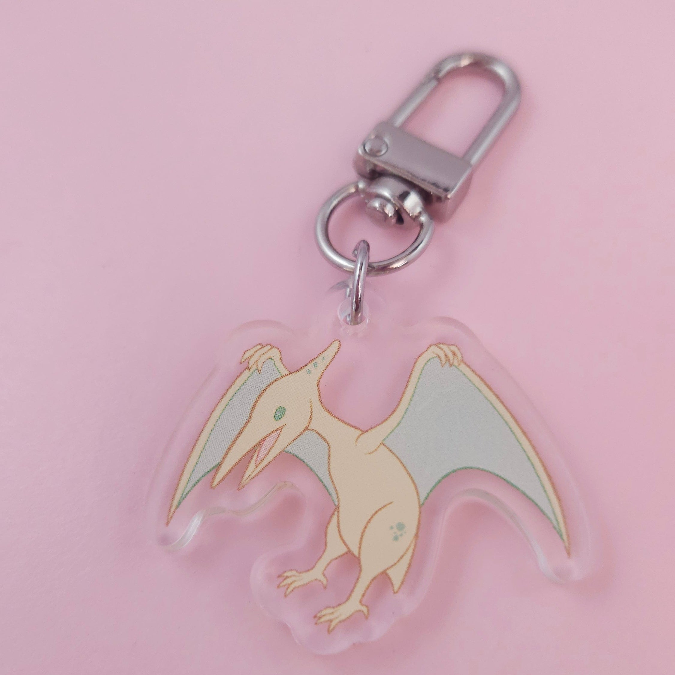 Dinosaur-shaped keychain on a pink background