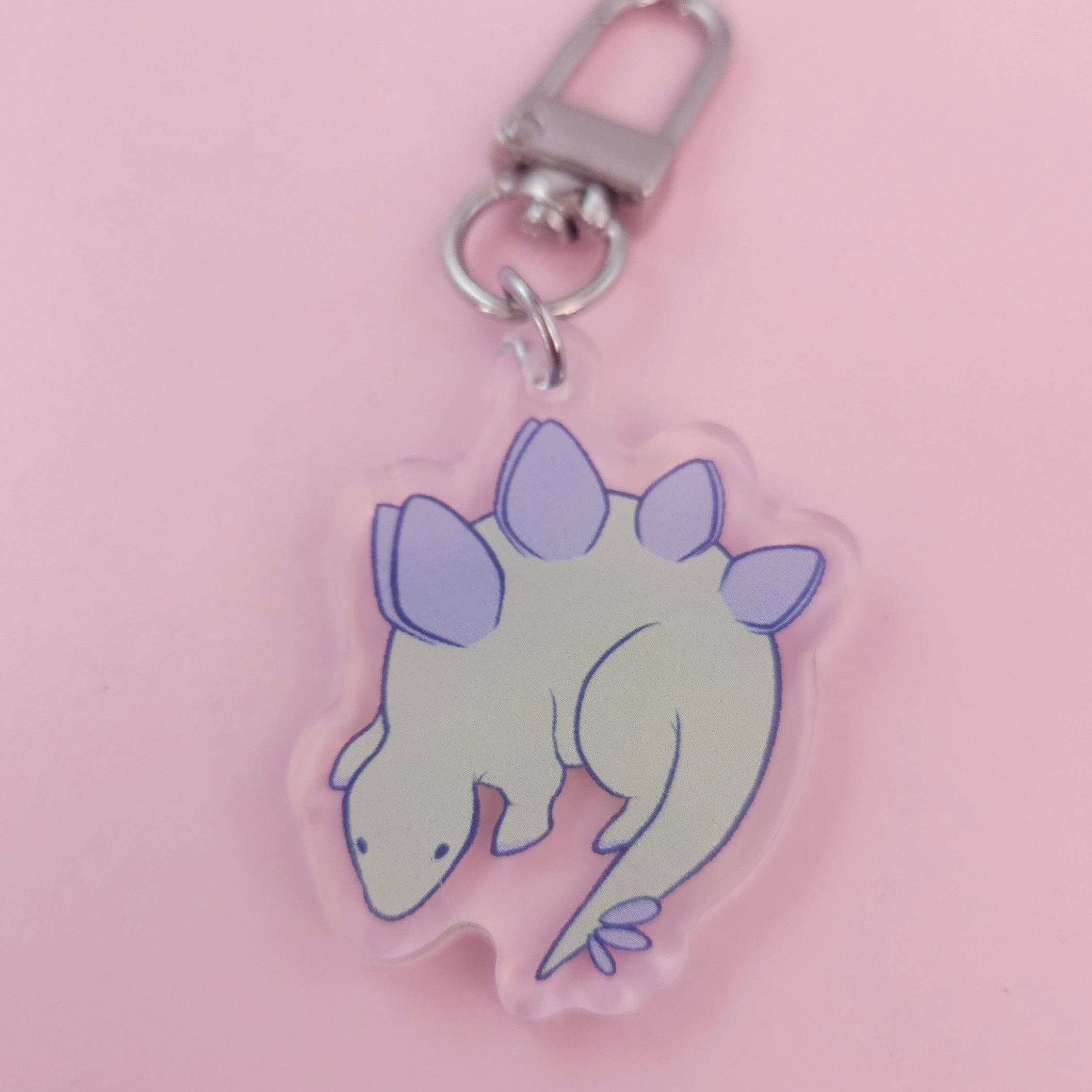 Keychain with a cartoon dinosaur design on a pink background