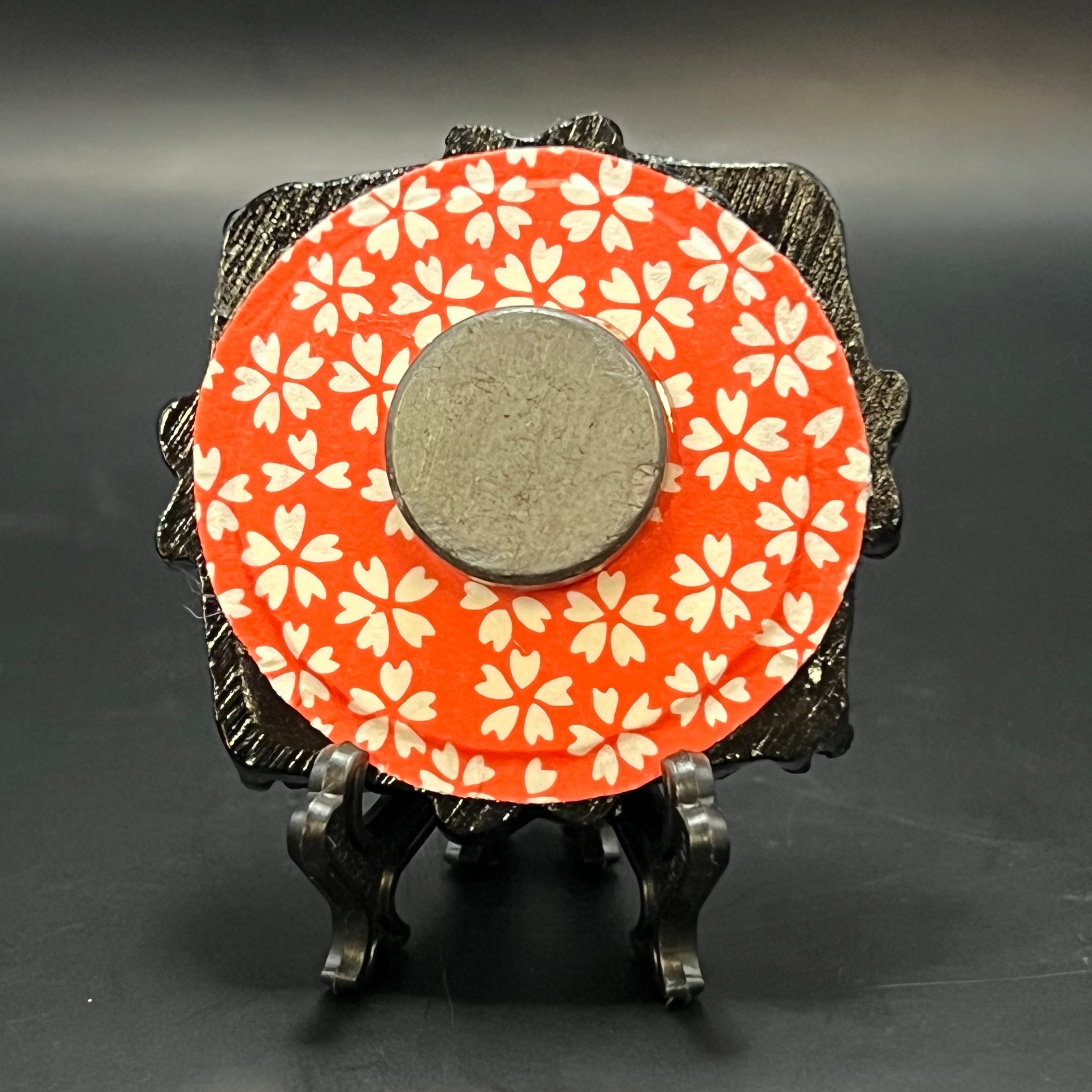 This is the Cherry Blossom Bloom Mini Painting by Chris Foster Design. This is showcasing the back. It is backed with red and white cherry blossom pattern origami paper. It is against a dark background.