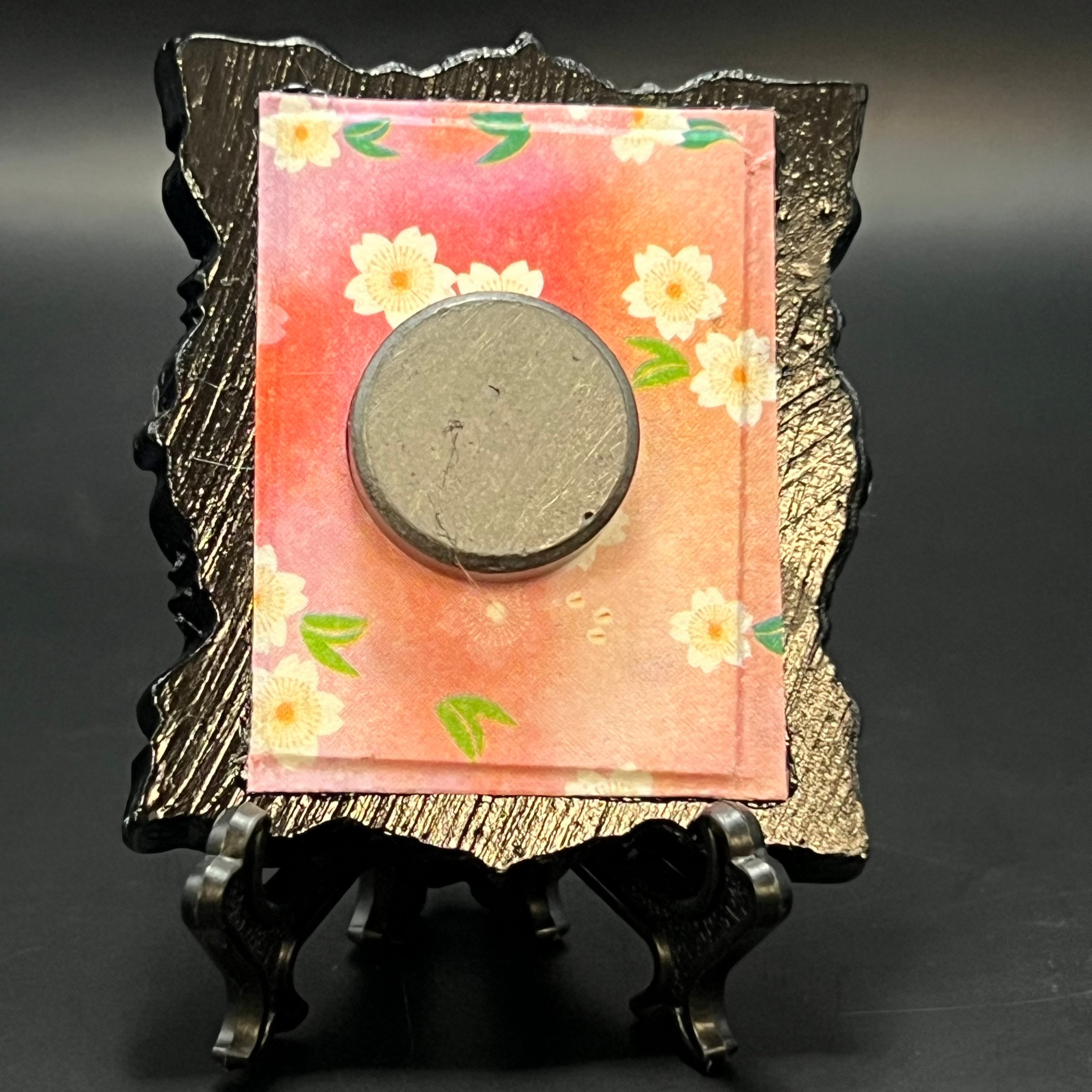This is the Cherry Blossom Vertical Mini Painting by Chris Foster Design. Ths is showcasing the back. Backed with warm pink cherry blossom patterned origami paper background. It is against a dark background.
