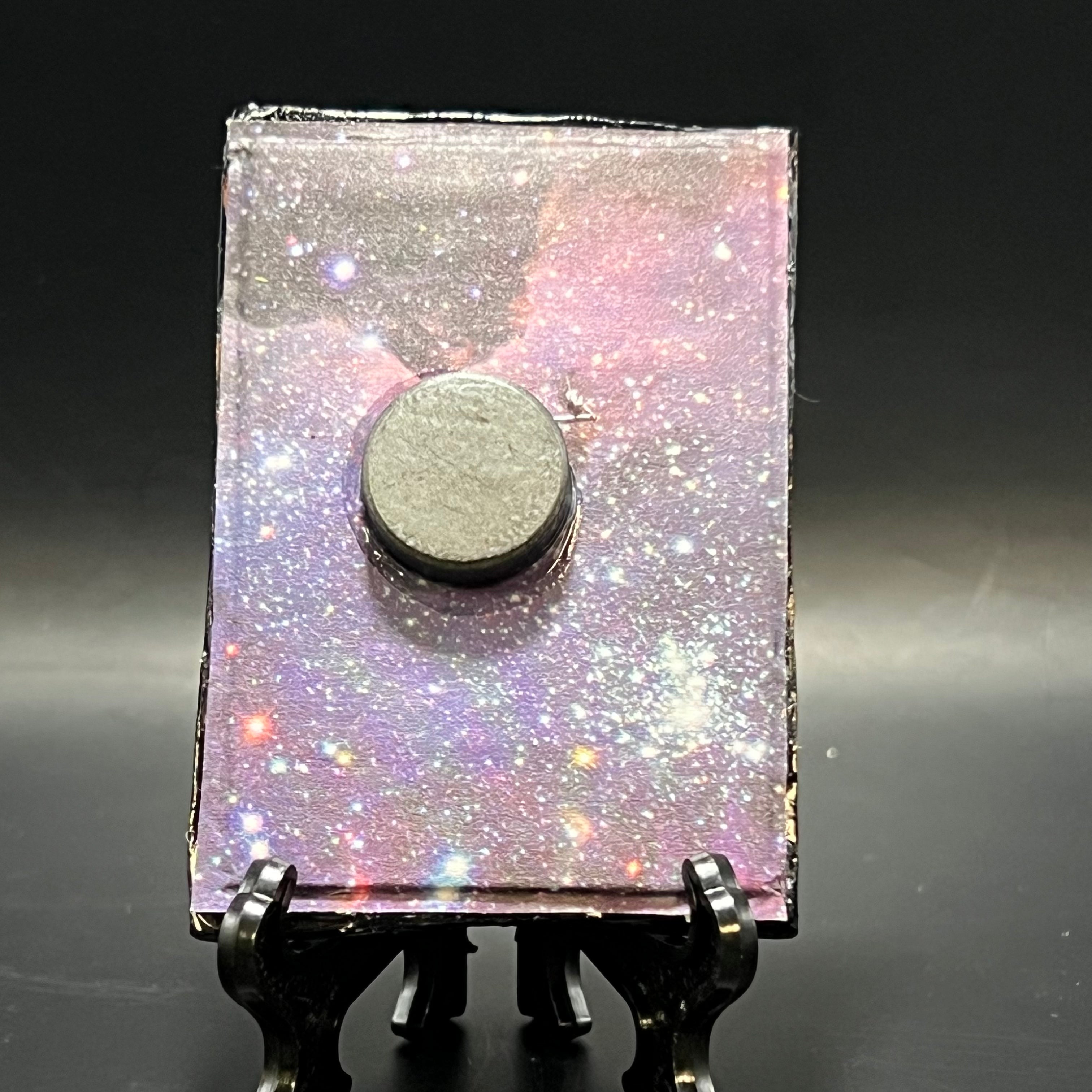 This is the Crescent Moon and Stars Nebula Mini Painting by Chris Foster Design. This is showcasing the back. Backed with purple blue and green nebula origami paper. It is against a dark background.