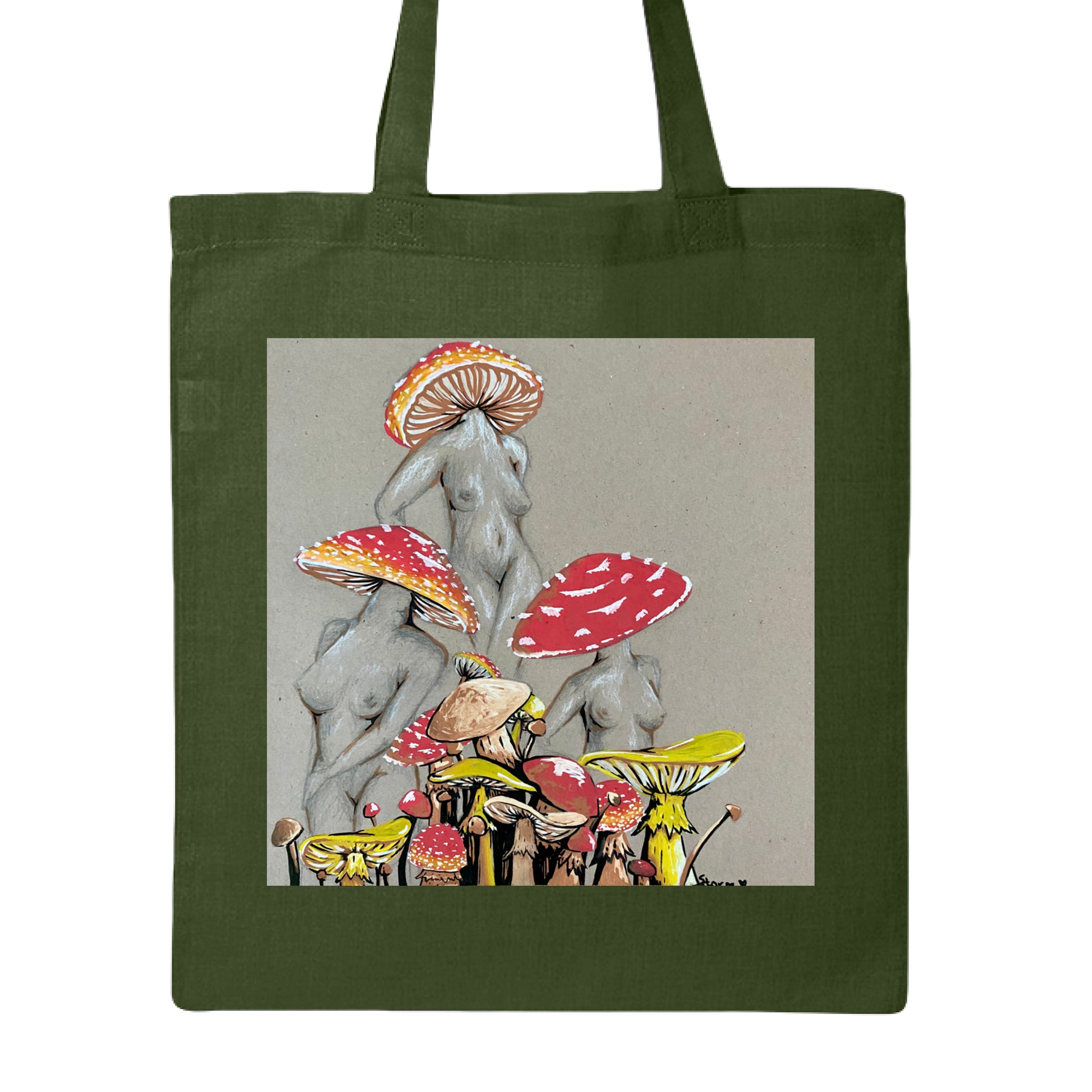 This is the Forest Miss Amanita Canvas Tote by Storm Garden Studio. This is showcasing the front. This illustration is on tan/grey background. There are three fusions of female human anatomy and mushroom fungi. Their heads are different styles of mushrooms, bodies are a gray/white outlined in brown. Below are different mushrooms and shapes with a mix of tan, red, white and yellow colors. The tote handles are color matched. It is against a white background.