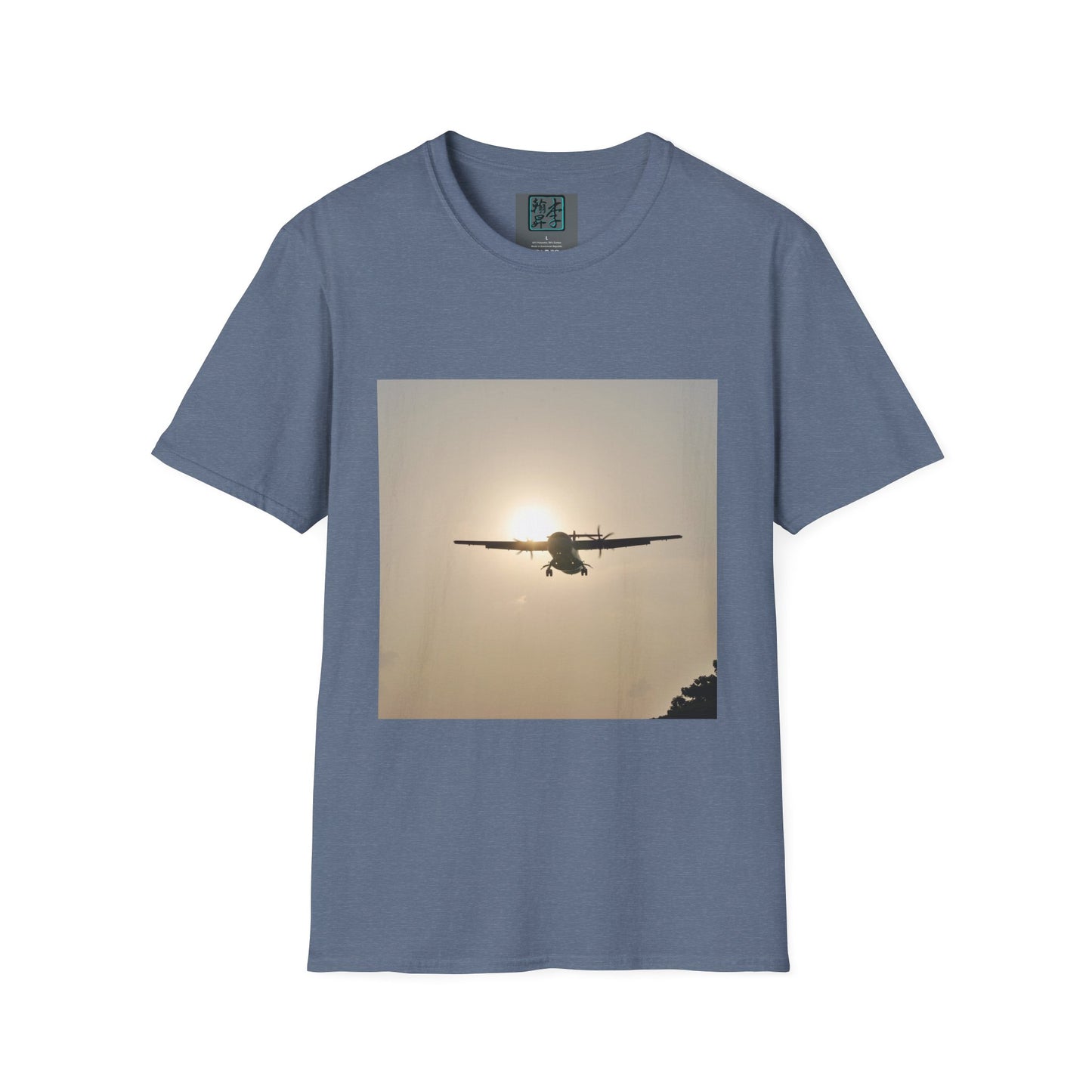This is the Heather Indigo Landing T-Shirt by Lee Hansheng Studios. This is an image of the front folded. On the inside of the shirt is the logo for the studio printed in black outlined in blue, gray size label with the print being white. The illustration is a rectangular design of an airplane landing. There is an orange/yellow sun with the shadowed plane. Some trees on the right end corner. The shirt is against a white background.
