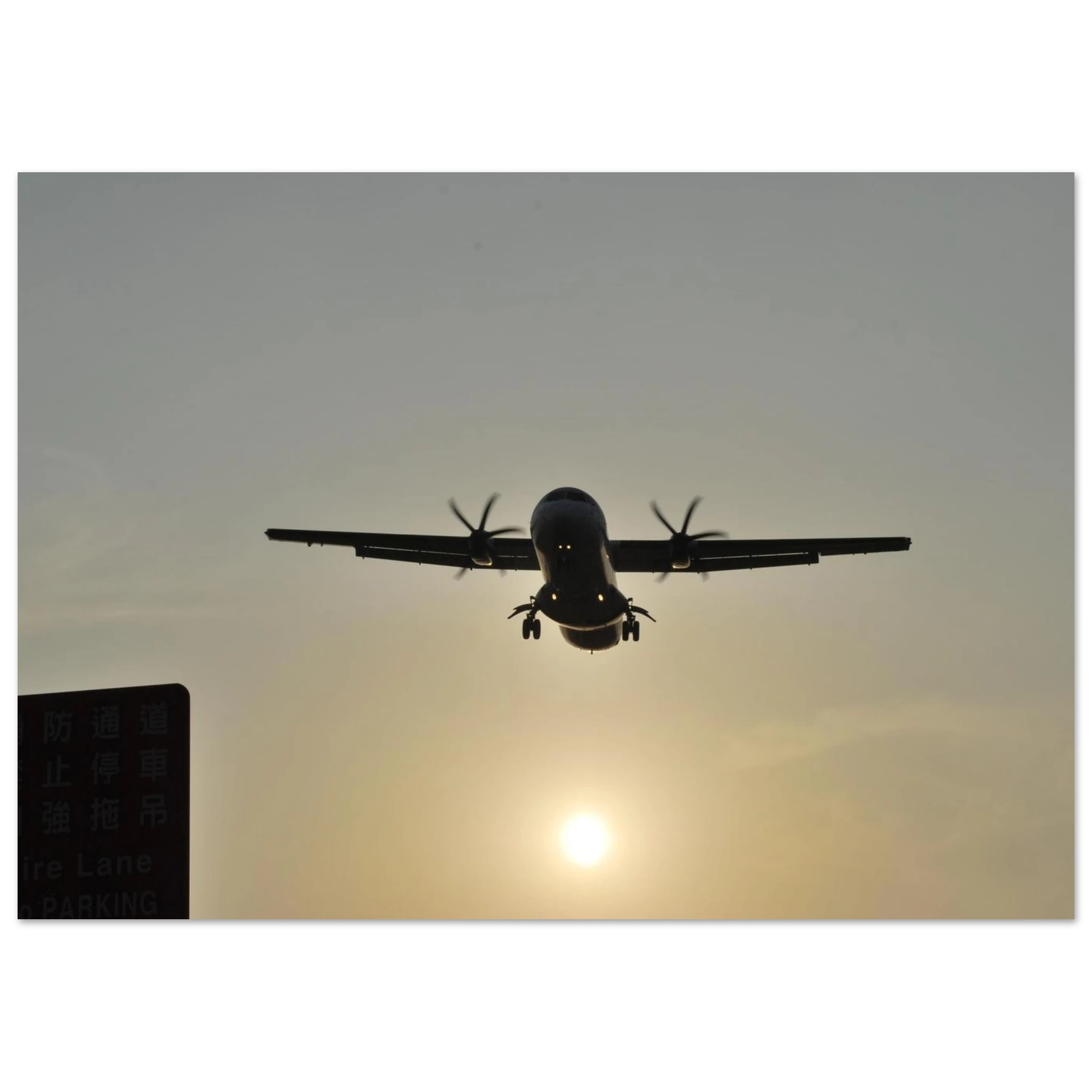 This is the 8" x 12" In Bound Print by Lee Hansheng Studios. It was captured at Songshan International Airport in Taipei, Taiwan, when the ATR 72 aircraft is taking flight. The airplane is flying against a sunset sky. On the left corner is a green sign in the shadows. 