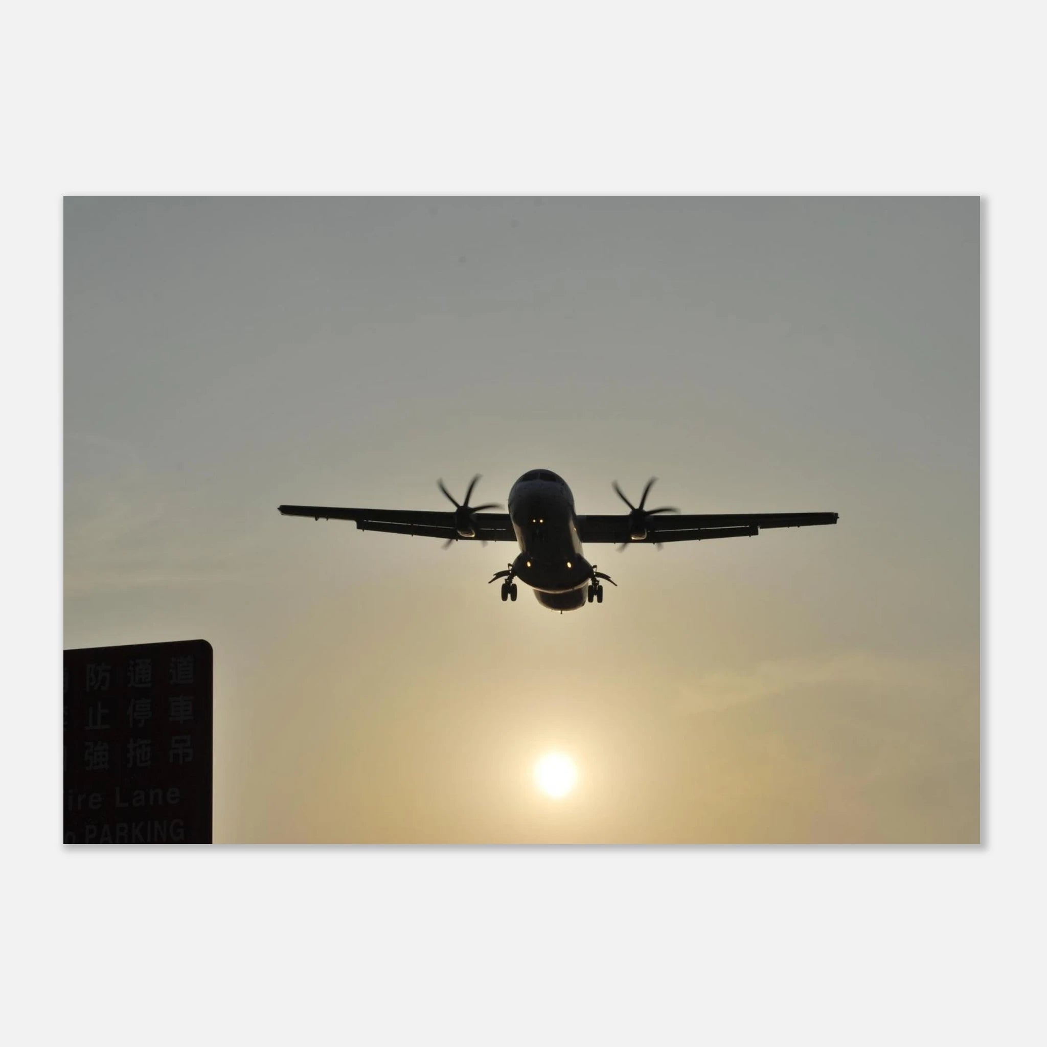 This is the 8" x 10" In Bound Print by Lee Hansheng Studios. It was captured at Songshan International Airport in Taipei, Taiwan, when the ATR 72 aircraft is taking flight. The airplane is flying against a sunset sky. On the left corner is a green sign in the shadows. The print is against a white background. 