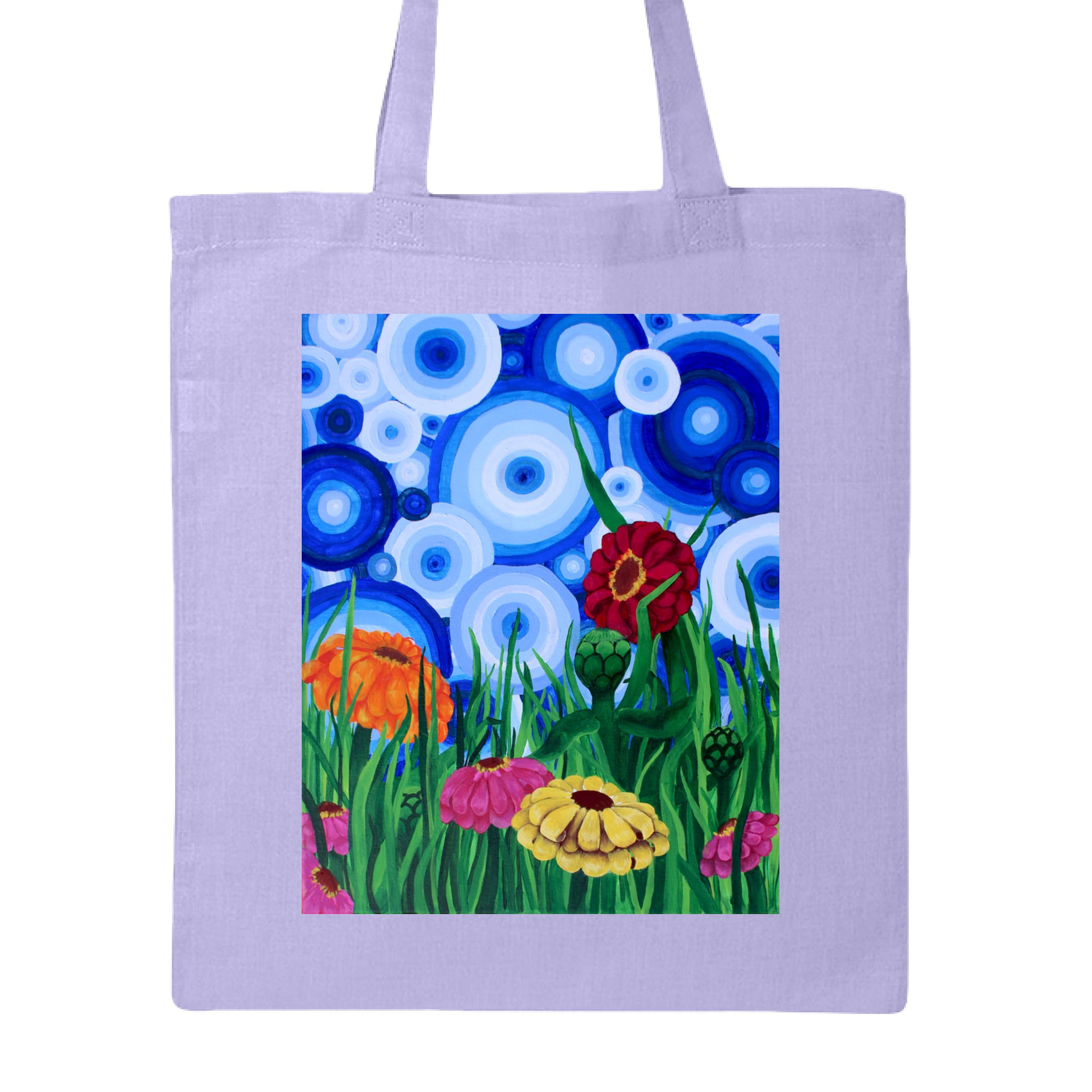 This is the Lavender Zinnia 2 Canvas Tote by Storm Garden Studio. This showcases the front of the tote. The rectangular illustration are bold and color zinnias like red, yellow and orange across tall green grass. The background has many different circles in blue, dark blue and white. The tote is against a white background.