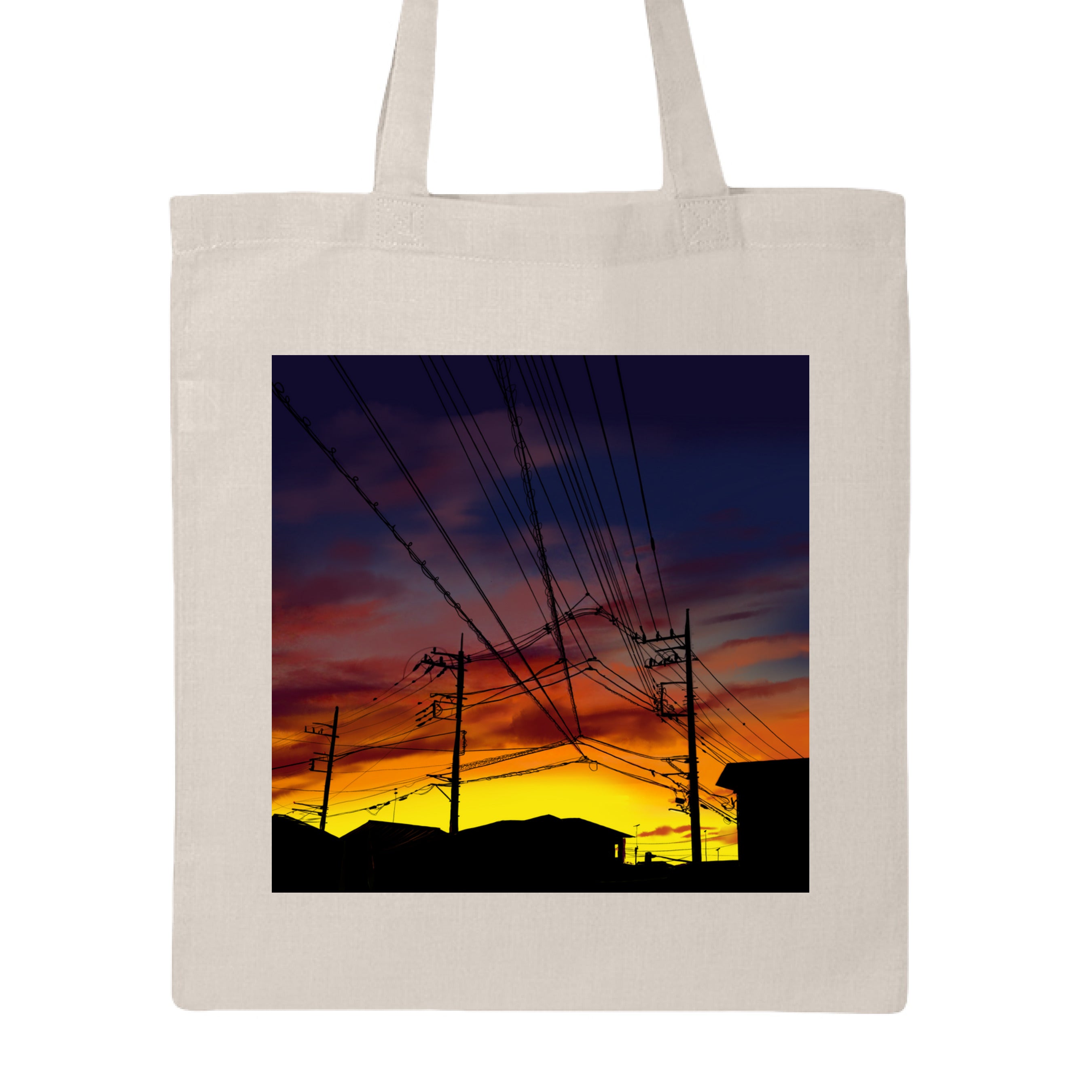 This is the Natural Saitama Sunset Canvas Tote by Lee Hansheng Studios. This showcases the front. The illustration shows the silhouettes of rooftops and power lines against a sky ablaze with golden yellows, deep oranges, and purples. The buildings are in the background on the bottom. The clouds are a mix of pink and reds. It is against a white background. 