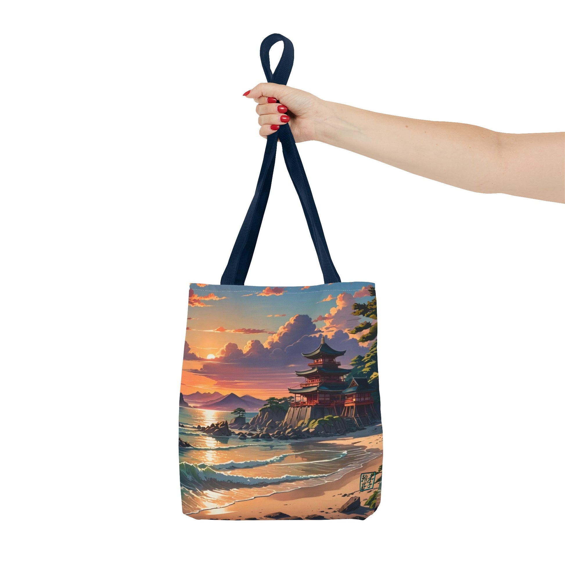 This is the Navy 13" x 13" Temple of Peace All-over Print Tote Bag by Lee Hansheng Studios.The illustration shows a setting red/orange sun above clouds,two blue roof,brown/red walled temples on the right on top of the hills,mountains,blue/white waves into sand and a forest to the right.On the bottom right corner is the logo printed in black for the studio and outlined in blue. A lady's upper arm is holding the tote from the handles to the middle from the right. She has red nailpolish on her nails. 