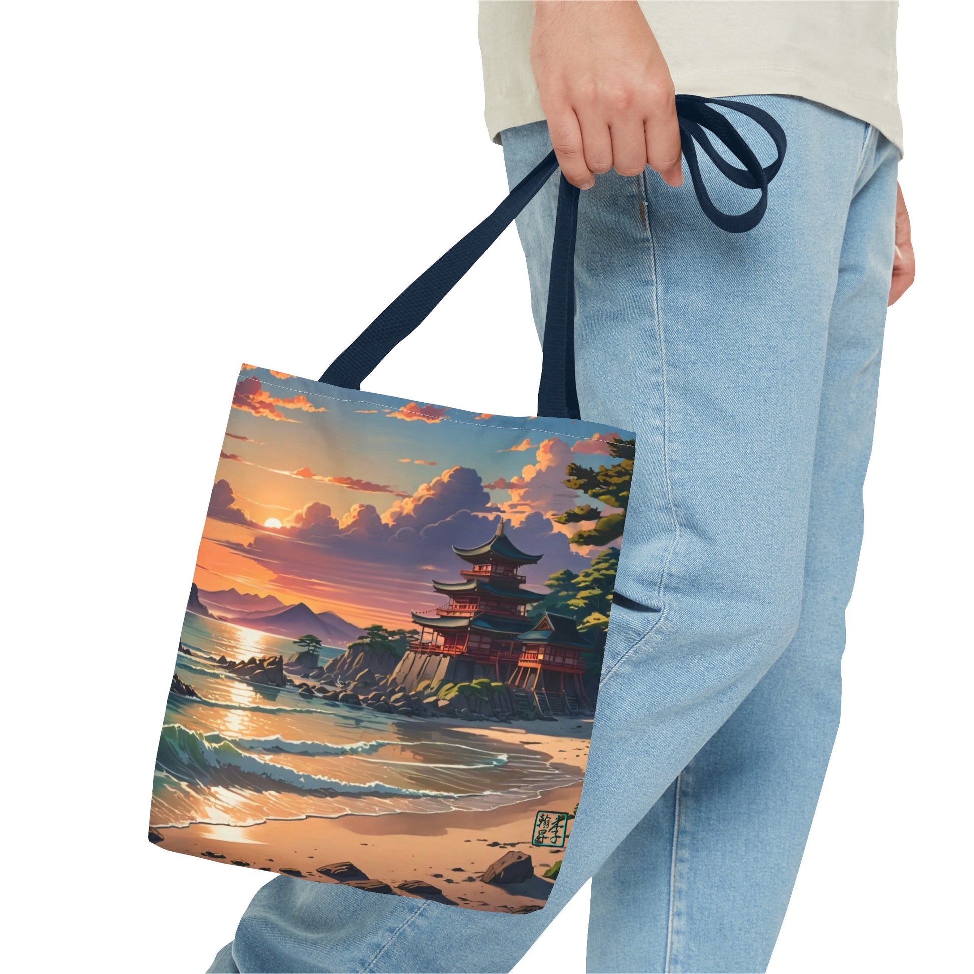 This is the Navy 16" x 16" Temple of Peace All-over Print Tote Bag by Lee Hansheng Studios.The illustration shows a setting red/orange sun above clouds,two blue roof,brown/red walled temples on the right on top of the hills,mountains,blue/white waves into sand and a forest to the right.On the bottom right corner is the logo printed in black for the studio and outlined in blue. The image is of a man wearing white tee, light jeans and right hand is holding the tote from waist down.