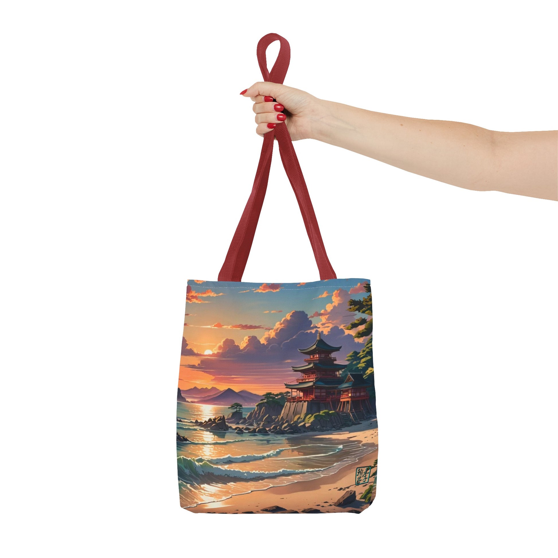 This is the Red 13" x 13" Temple of Peace All-over Print Tote Bag by Lee Hansheng Studios.The illustration shows a setting red/orange sun above clouds,two blue roof,brown/red walled temples on the right on top of the hills,mountains,blue/white waves into sand and a forest to the right.On the bottom right corner is the logo printed in black for the studio and outlined in blue. A lady's upper arm is holding the tote from the handles to the middle from the right. She has red nailpolish on her nails. 