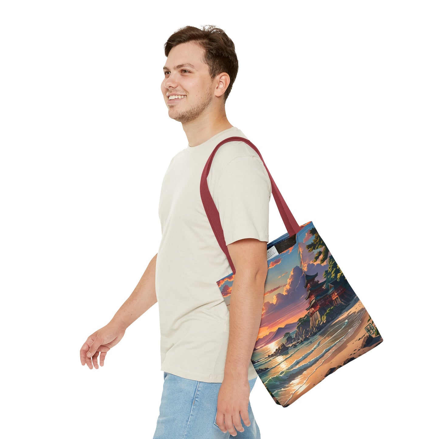 This is the Red 13" x 13" Temple of Peace All-over Print Tote Bag by Lee Hansheng Studios.The illustration shows a setting red/orange sun above clouds,two blue roof,brown/red walled temples on the right on top of the hills,mountains,blue/white waves into sand and a forest to the right.On the bottom right corner is the logo printed in black for the studio and outlined in blue. A man walking to the left, smiling, wearing white tee, light jeans with tote hanging on his shoulder and swinging his arms.