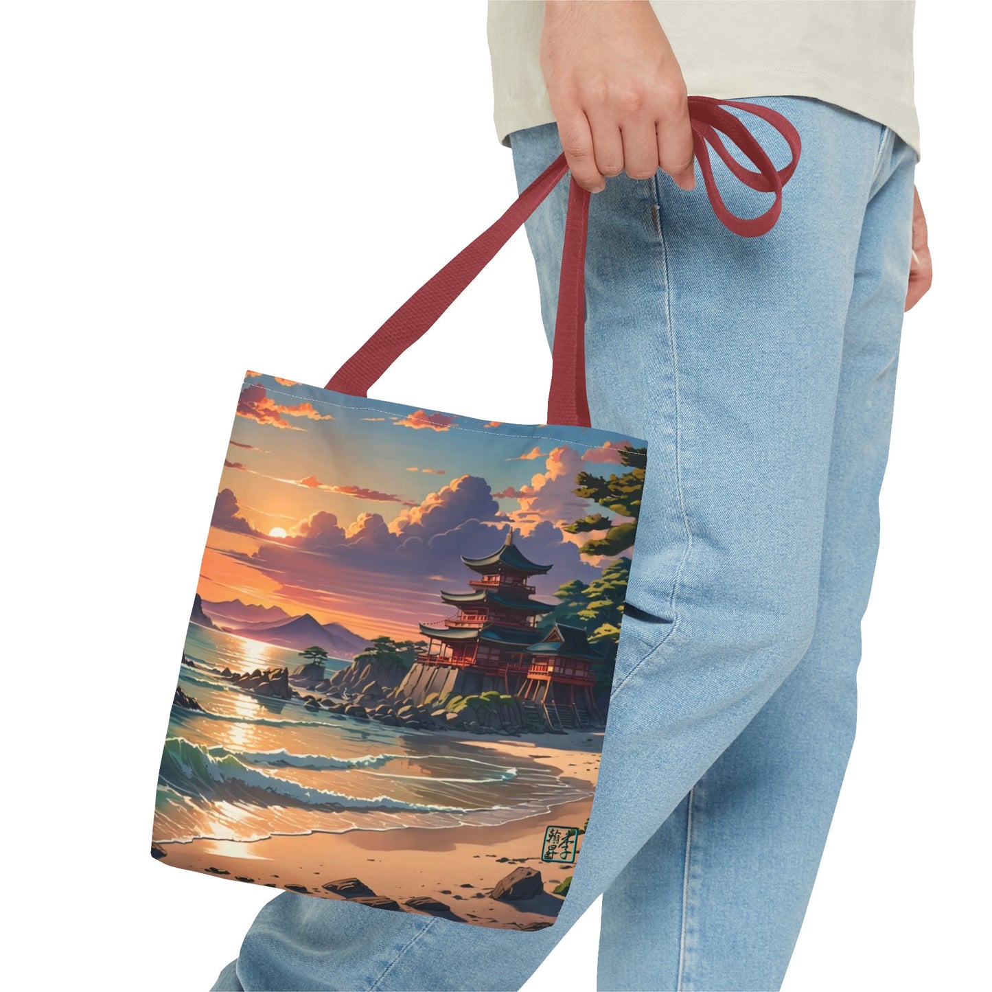 This is the Red 16" x 16" Temple of Peace All-over Print Tote Bag by Lee Hansheng Studios.The illustration shows a setting red/orange sun above clouds,two blue roof,brown/red walled temples on the right on top of the hills,mountains,blue/white waves into sand and a forest to the right.On the bottom right corner is the logo printed in black for the studio and outlined in blue. The image is of a man wearing white tee, light jeans and right hand is holding the tote from waist down.