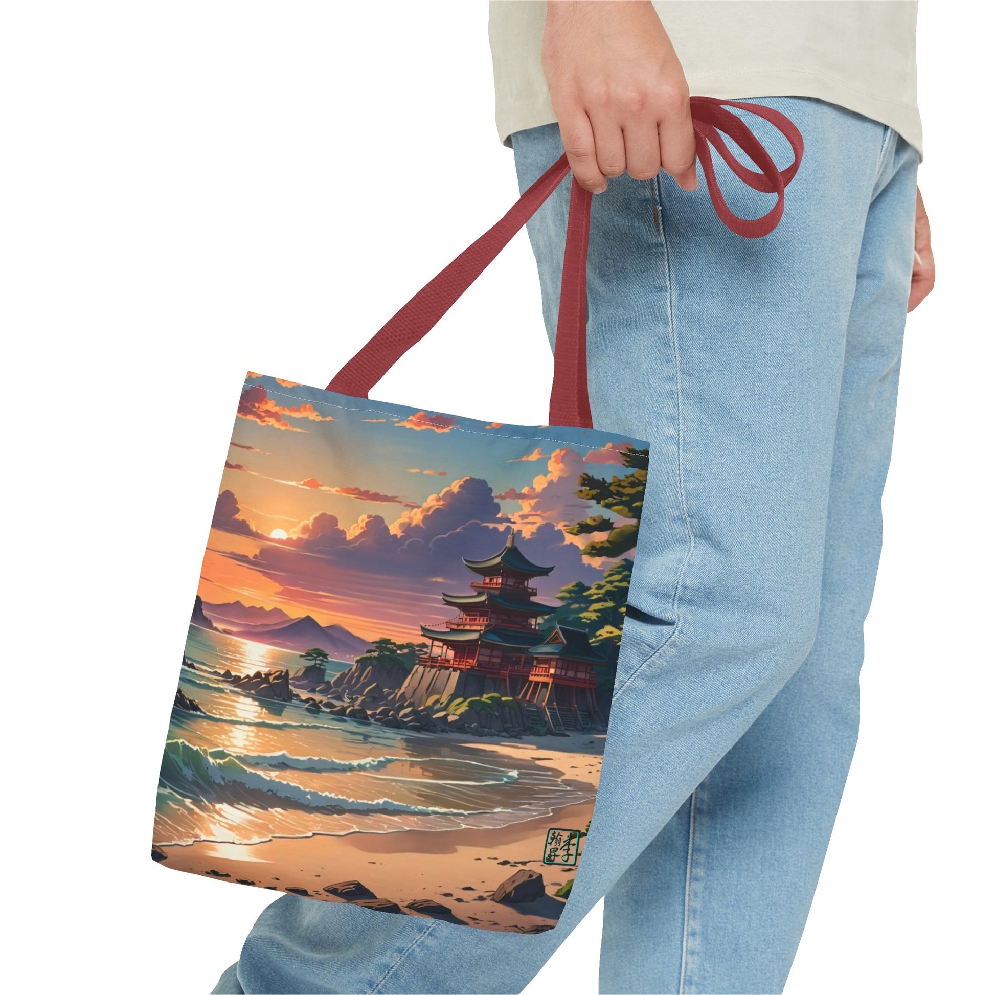 This is the Red 16" x 16" Temple of Peace All-over Print Tote Bag by Lee Hansheng Studios.The illustration shows a setting red/orange sun above clouds,two blue roof,brown/red walled temples on the right on top of the hills,mountains,blue/white waves into sand and a forest to the right.On the bottom right corner is the logo printed in black for the studio and outlined in blue. The image is of a man wearing white tee, light jeans and right hand is holding the tote from waist down.