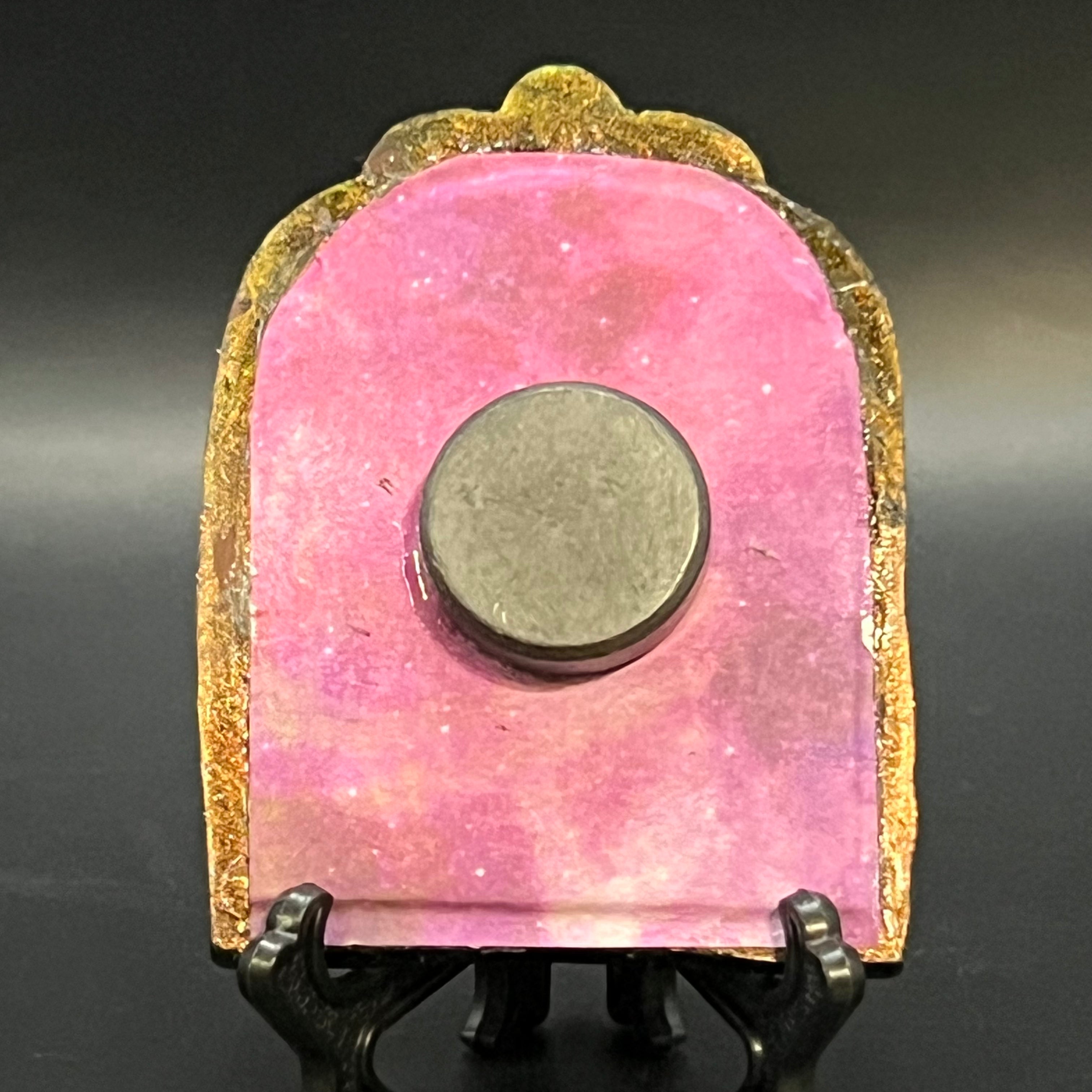 This is the Starry Orbit Mini Painting by Chris Foster Design. This is showcasing the back. It is backed with pink crystal/twinkling oragami paper, a round magnet, black stand and is against a dark background.