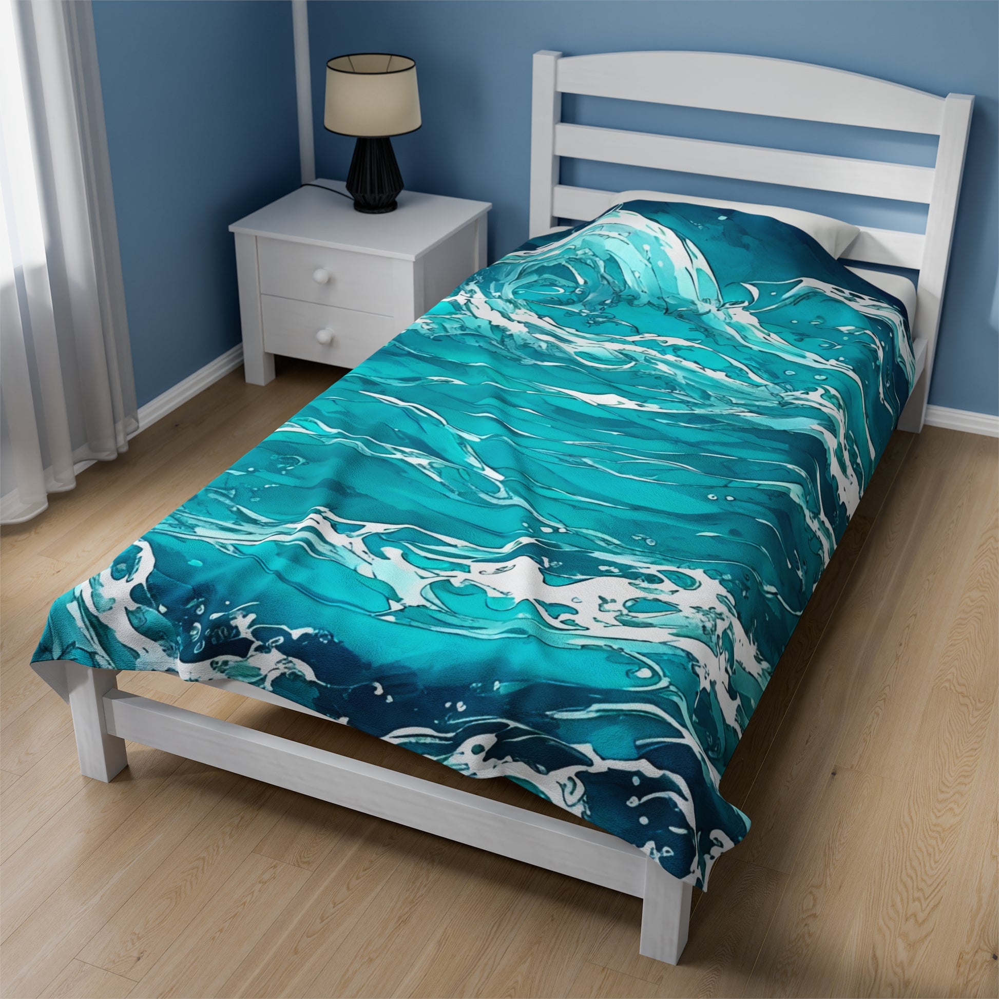 The Swirling Seas design by Lee Hansheng Studios is centered on a twin white wooden bed, dressed with a white duvet and complemented by a white wood slat headboard. The blanket features waves in mixed hues of blues and greens, swirling together with foam caps. A white nightstand in the back left corner holds a black lamp with round cream lamp shade with black trim. The room has sky blue walls with white trim, light wood floors, and a window on the left with sheer white curtains that let in soft light. 