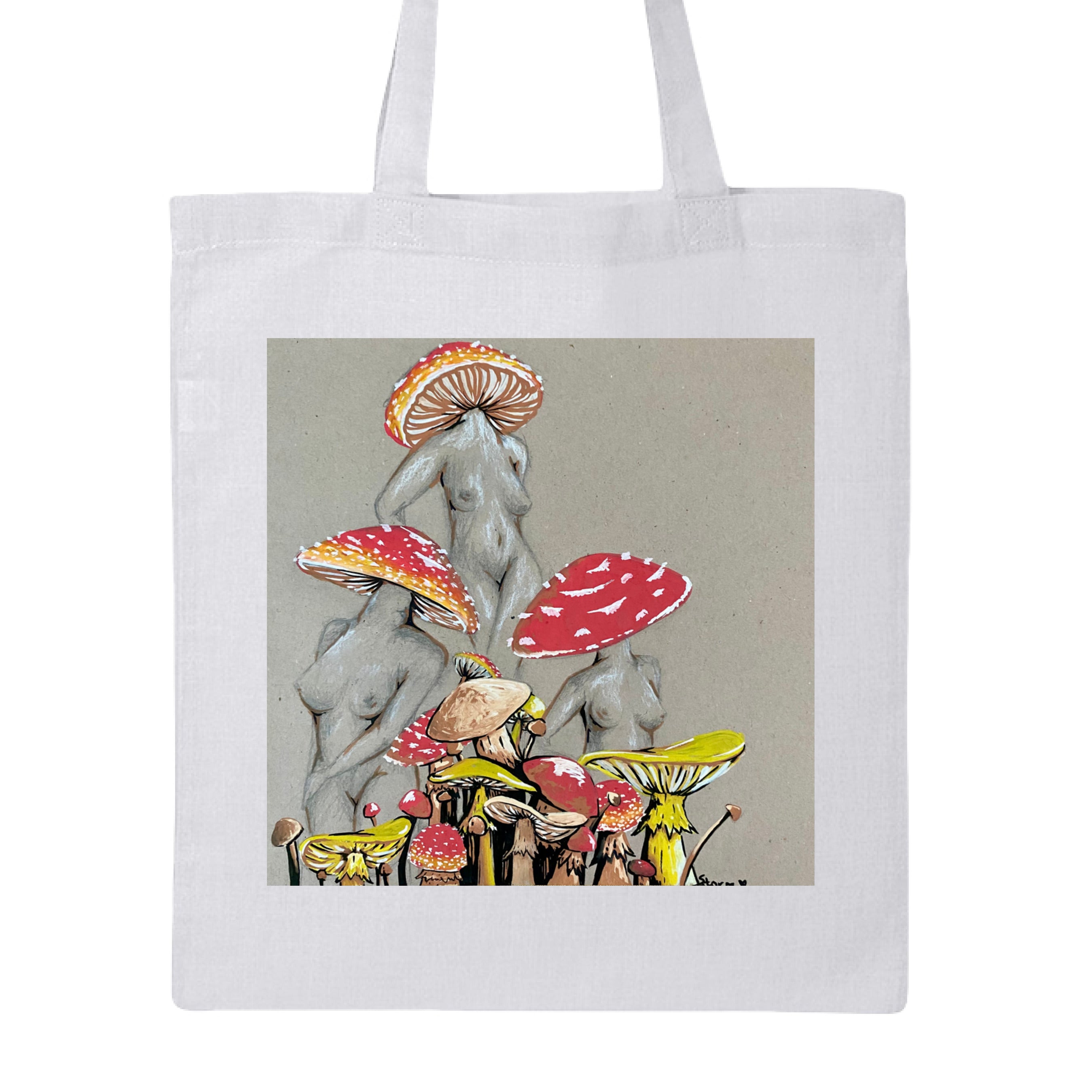 This is the White Miss Amanita Canvas Tote by Storm Garden Studio. This is showcasing the front. This illustration is on tan/grey background. There are three fusions of female human anatomy and mushroom fungi. Their heads are different styles of mushrooms, bodies are a gray/white outlined in brown. Below are different mushrooms and shapes with a mix of tan, red, white and yellow colors. The tote handles are color matched. It is against a white background.
