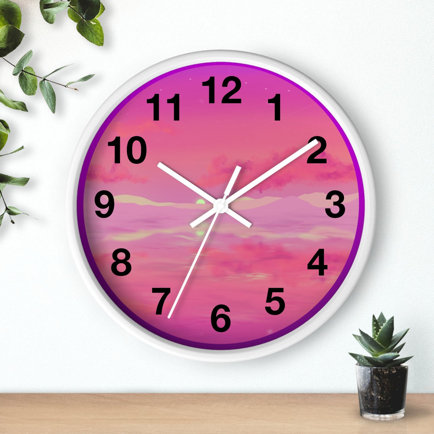 This is the 10" White Base Pink Dreamscape Wall Clock with white hands by Lee Hansheng Studios.The front of the image with two white clock hands, black numerals and the illustration behind it.The illustration has the sky and clouds. Different pinks and hues blended into the clouds and spreads outwards.There are dark purples on the side and yellows near the middle of the art piece. It is on a white background with leaves to the left, succulent plan on the right with a wooden board. 