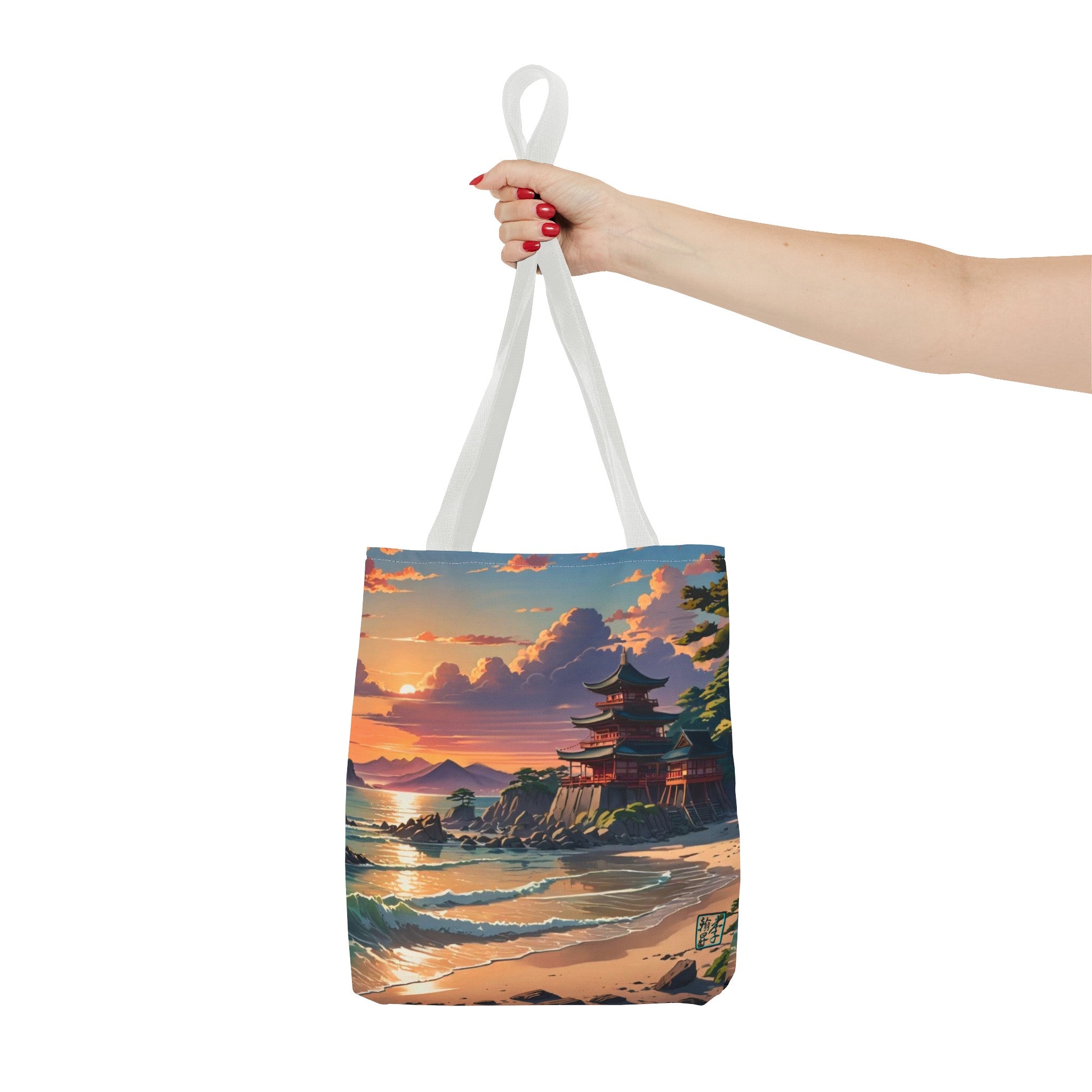 This is the White 13" x 13" Temple of Peace All-over Print Tote Bag by Lee Hansheng Studios.The illustration shows a setting red/orange sun above clouds,two blue roof,brown/red walled temples on the right on top of the hills,mountains,blue/white waves into sand and a forest to the right.On the bottom right corner is the logo printed in black for the studio and outlined in blue. A lady's upper arm is holding the tote from the handles to the middle from the right. She has red nailpolish on her nails. 