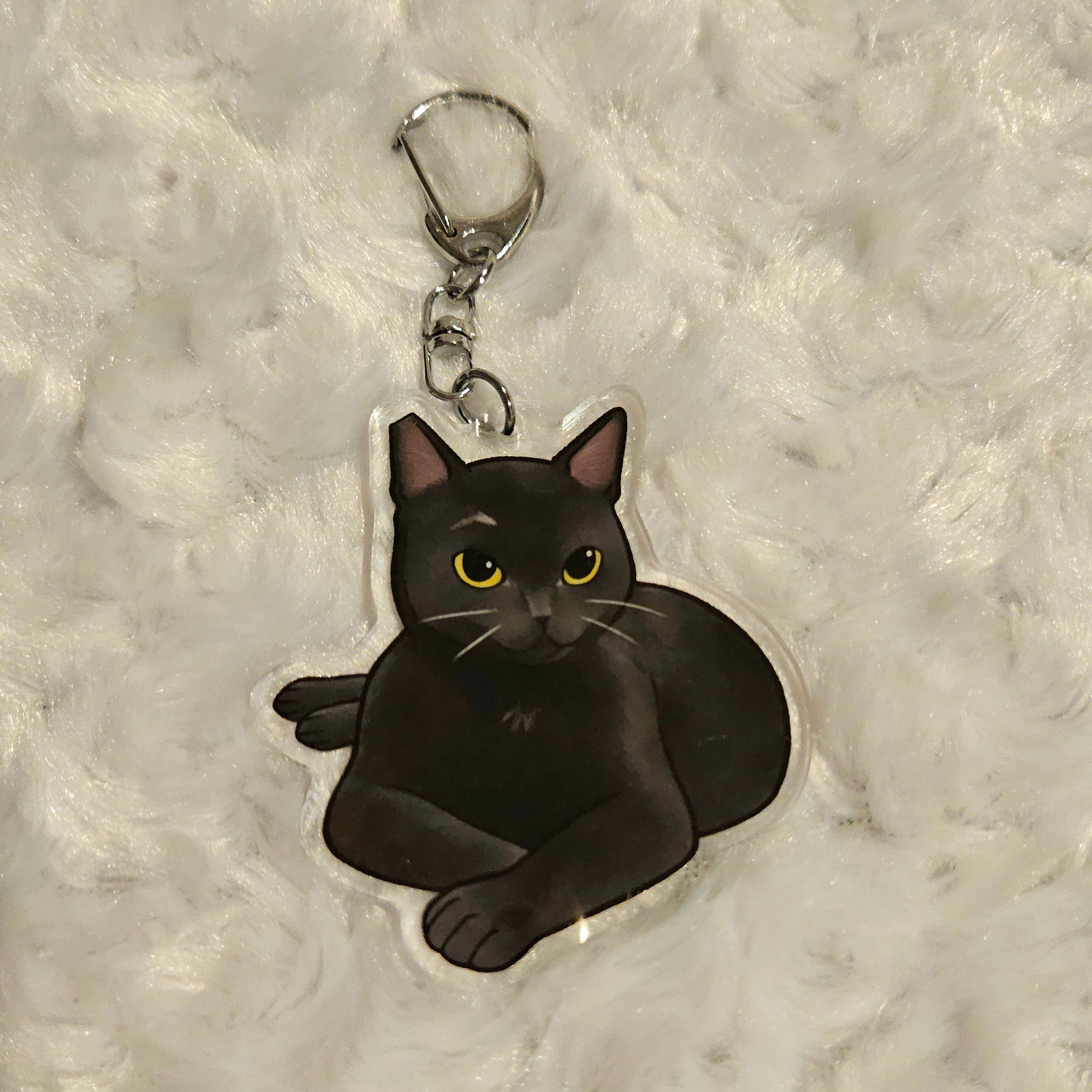 Black cat keychain on a textured gray background