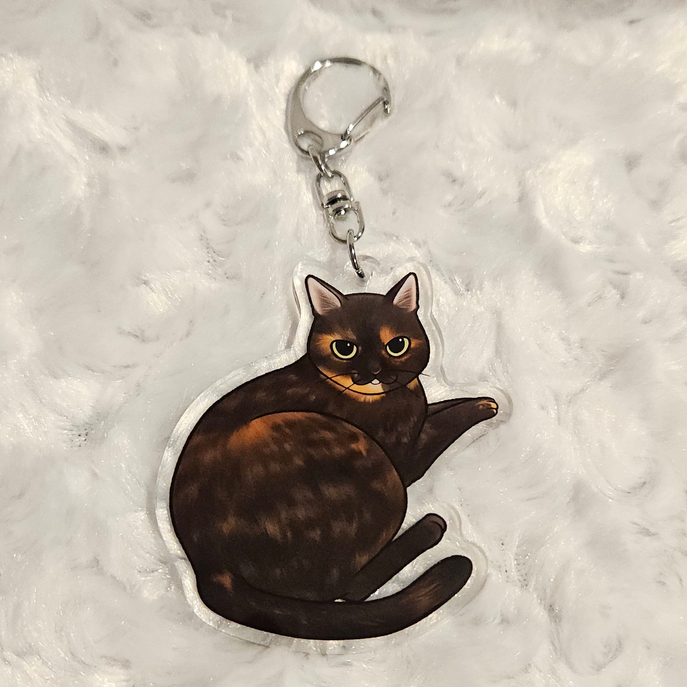 Keychain with a tortoiseshell cat design on a textured gray background