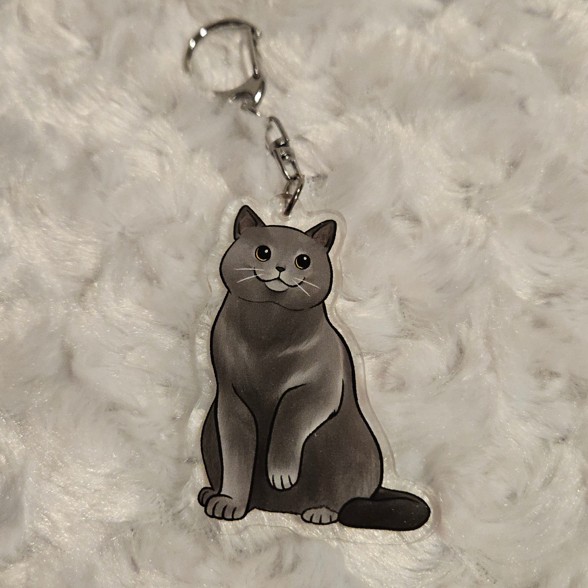 Cat-shaped keychain on a textured gray surface