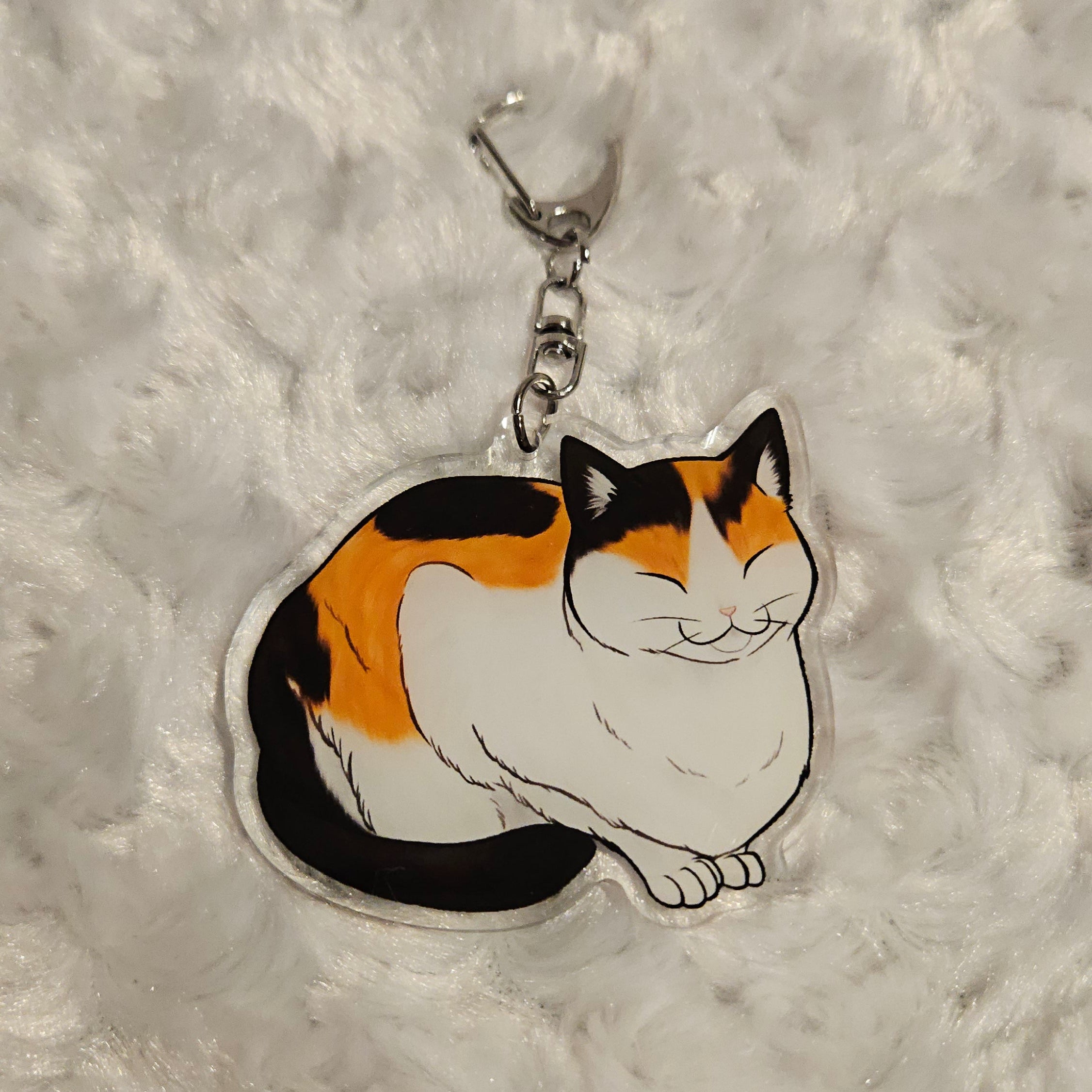 Keychain with a cartoon cat design on a textured gray background