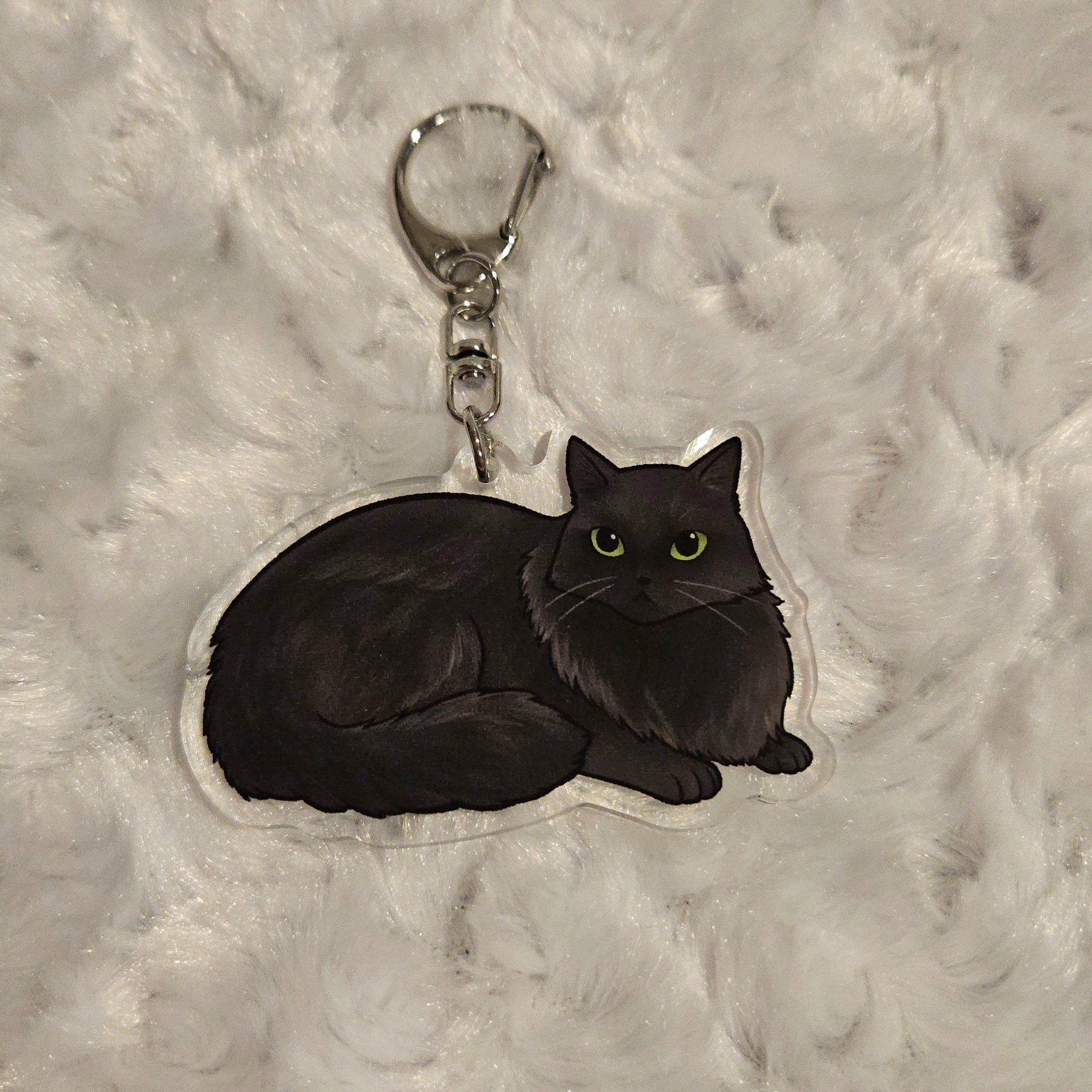 Black cat-shaped keychain on a textured gray background