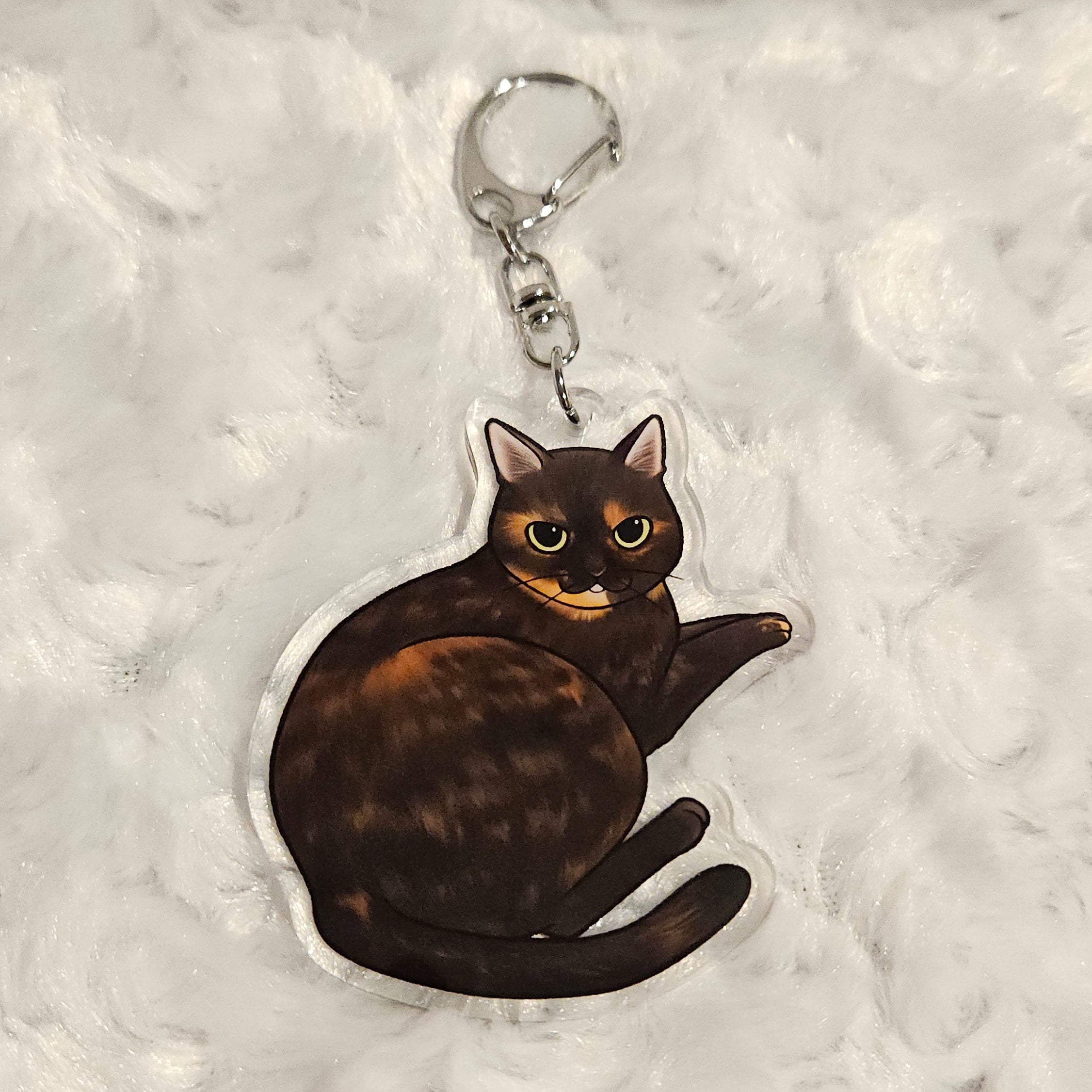 Keychain with a tortoiseshell cat design on a textured gray background