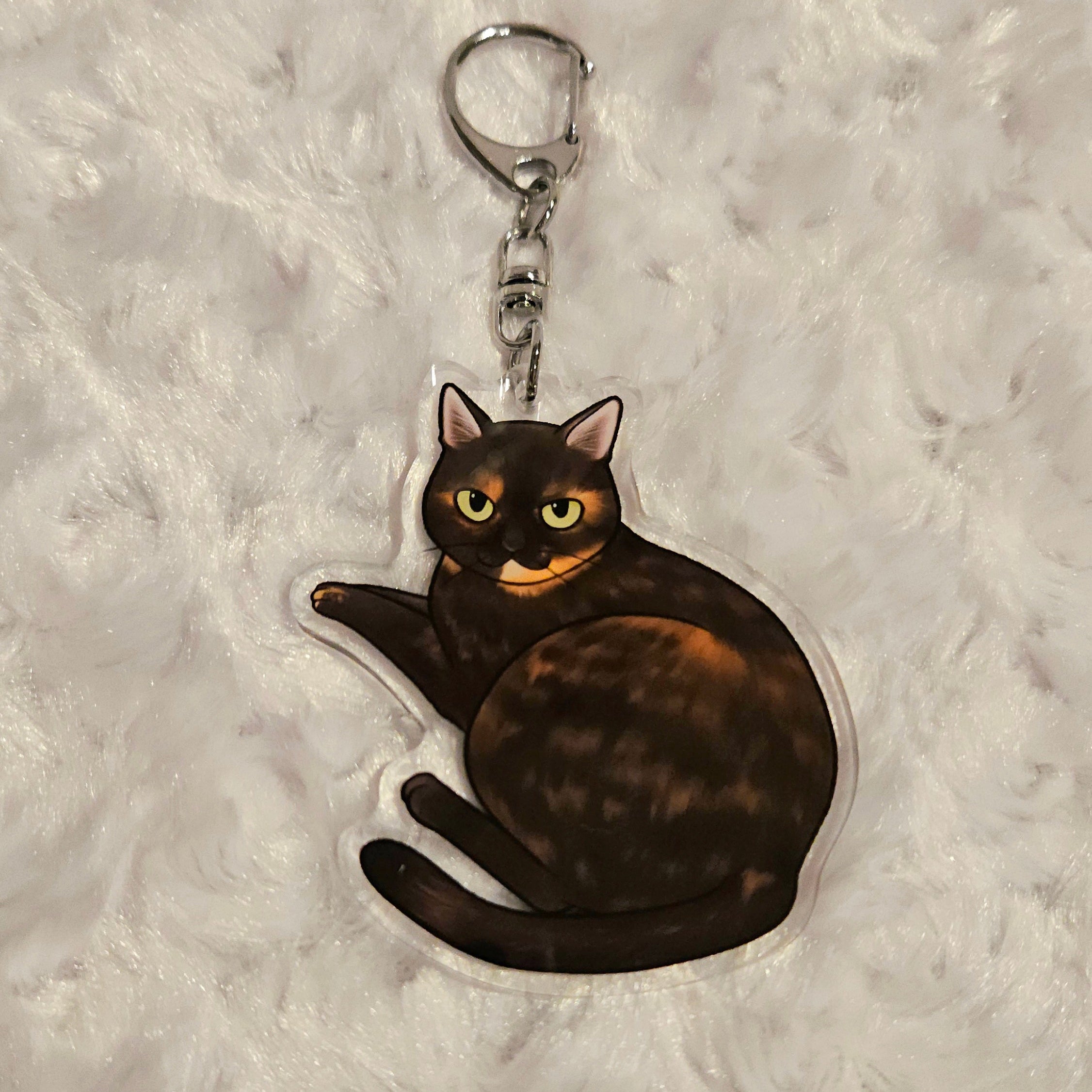 Keychain with a tortoiseshell cat design on a textured gray background