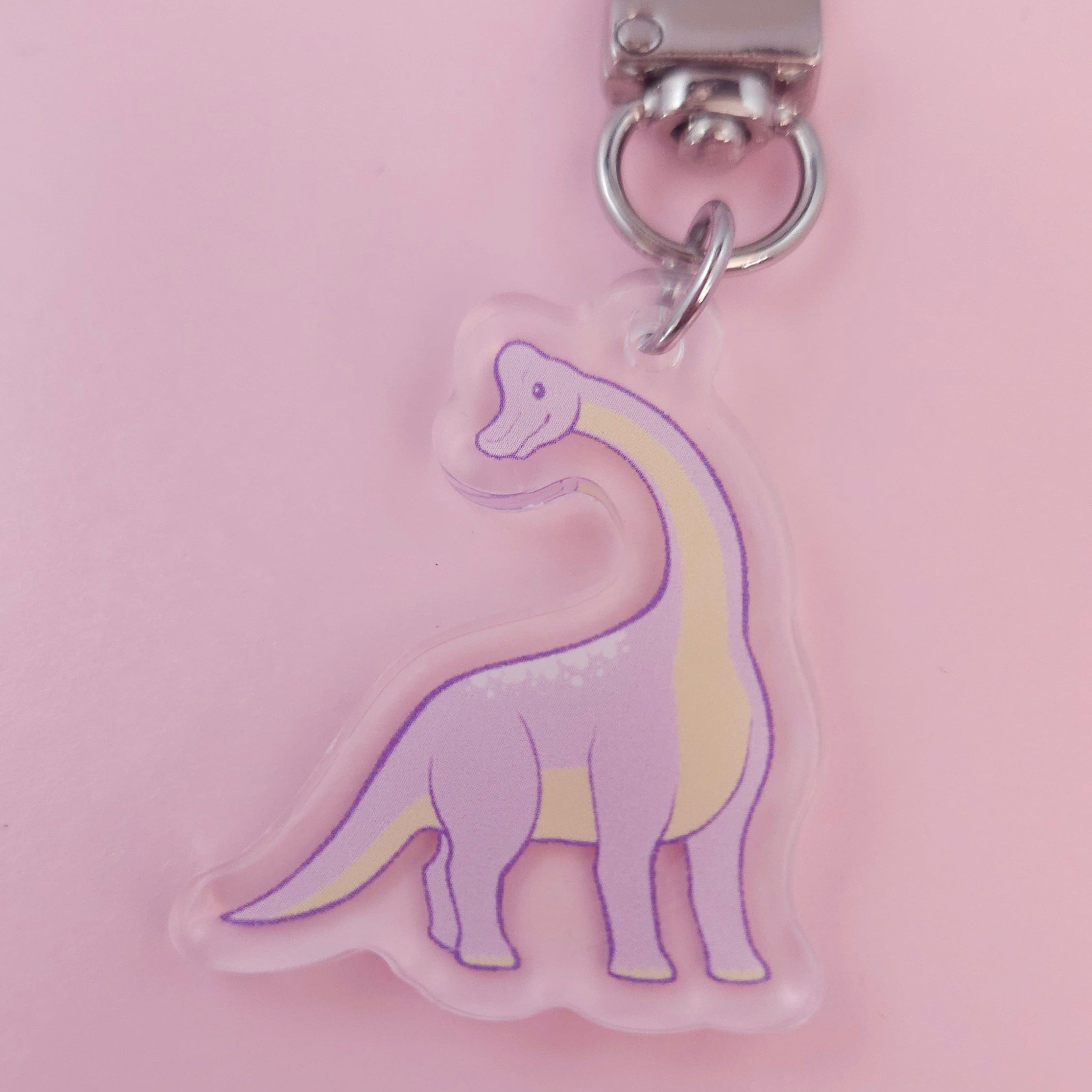 Keychain with a brachiosaurus design on a pink background